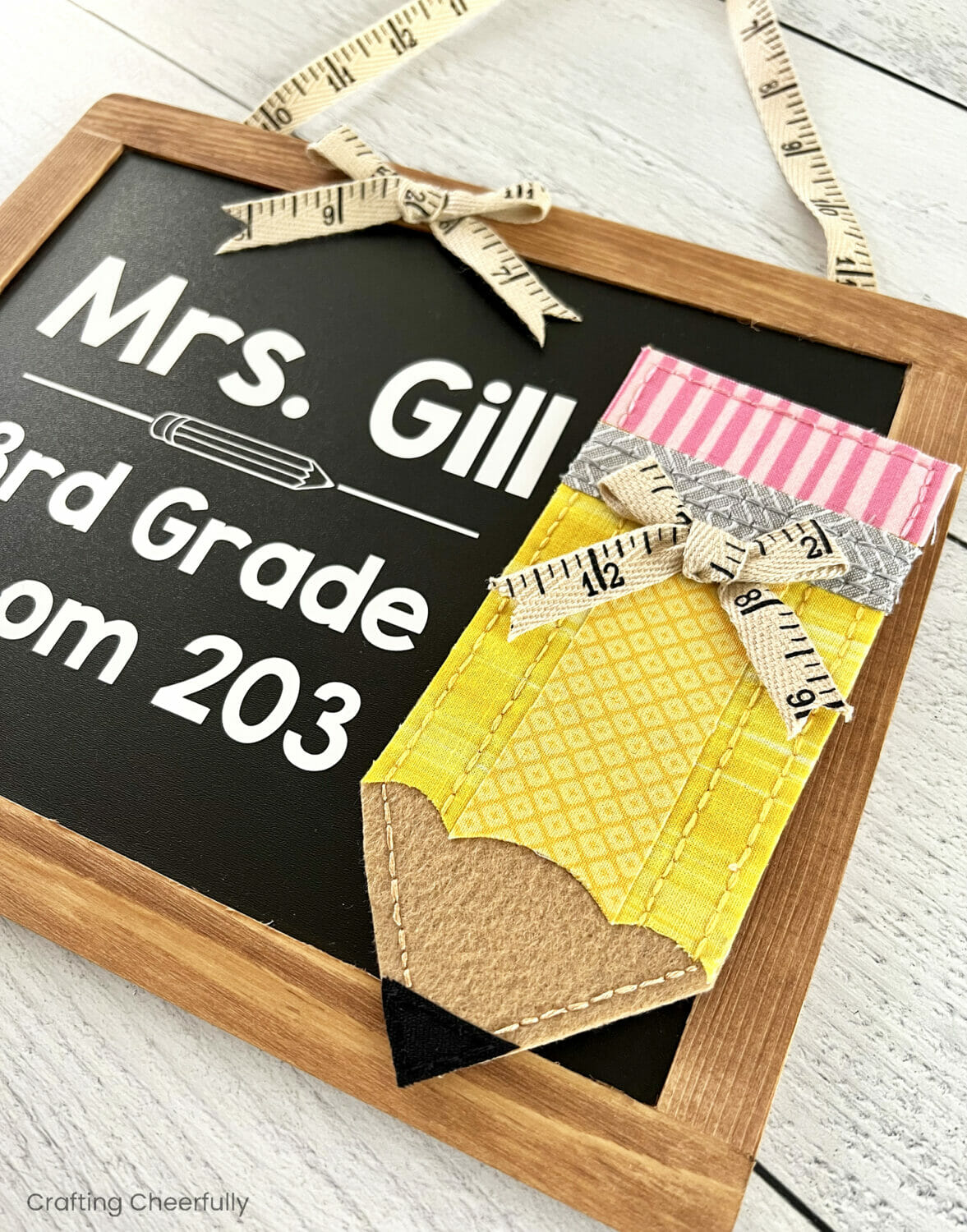 A fabric and felt pencil displayed on one side of a small chalkboard. 