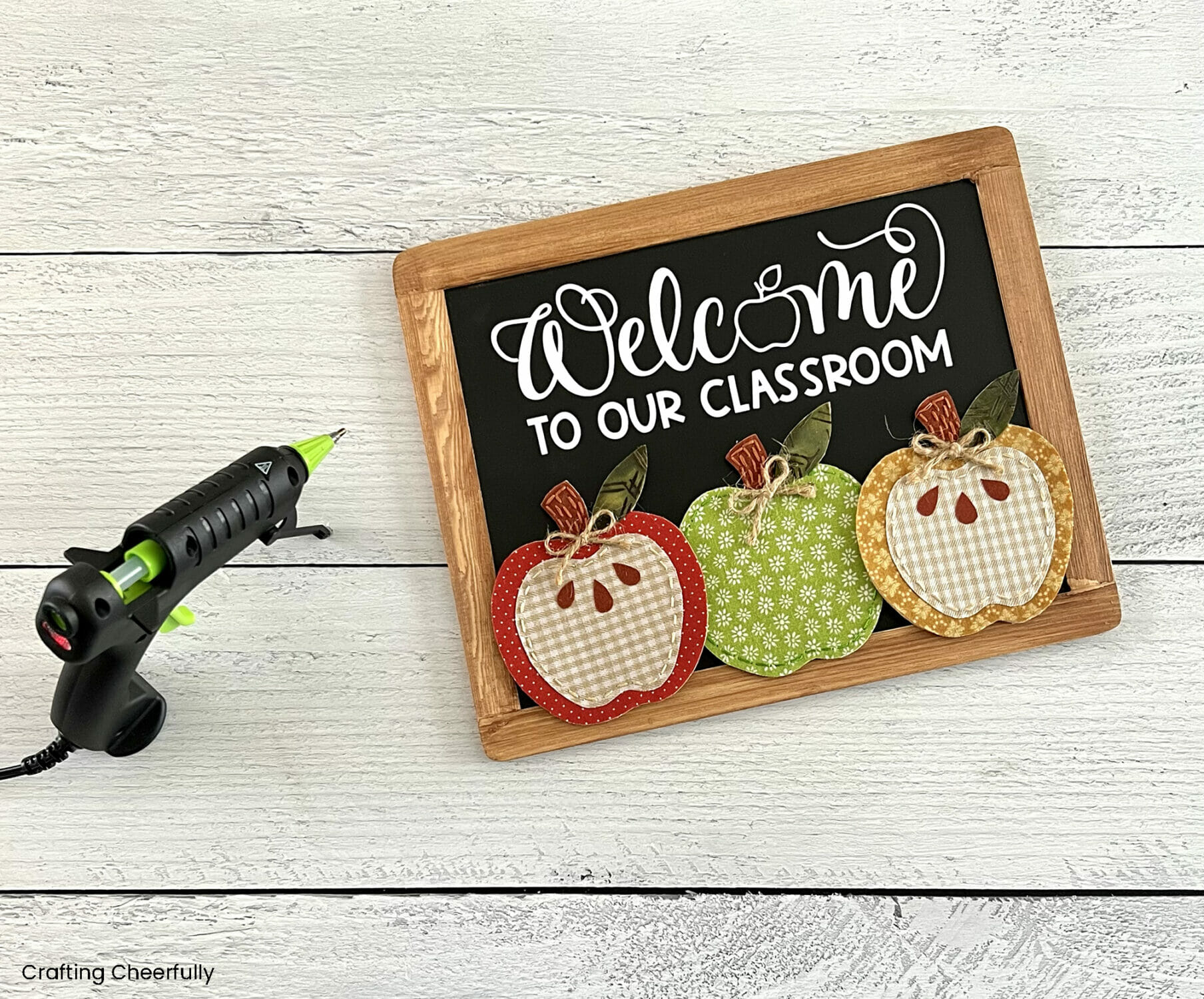A hot glue gun used to add felt and fabric apples to the bottom of the chalkboard.