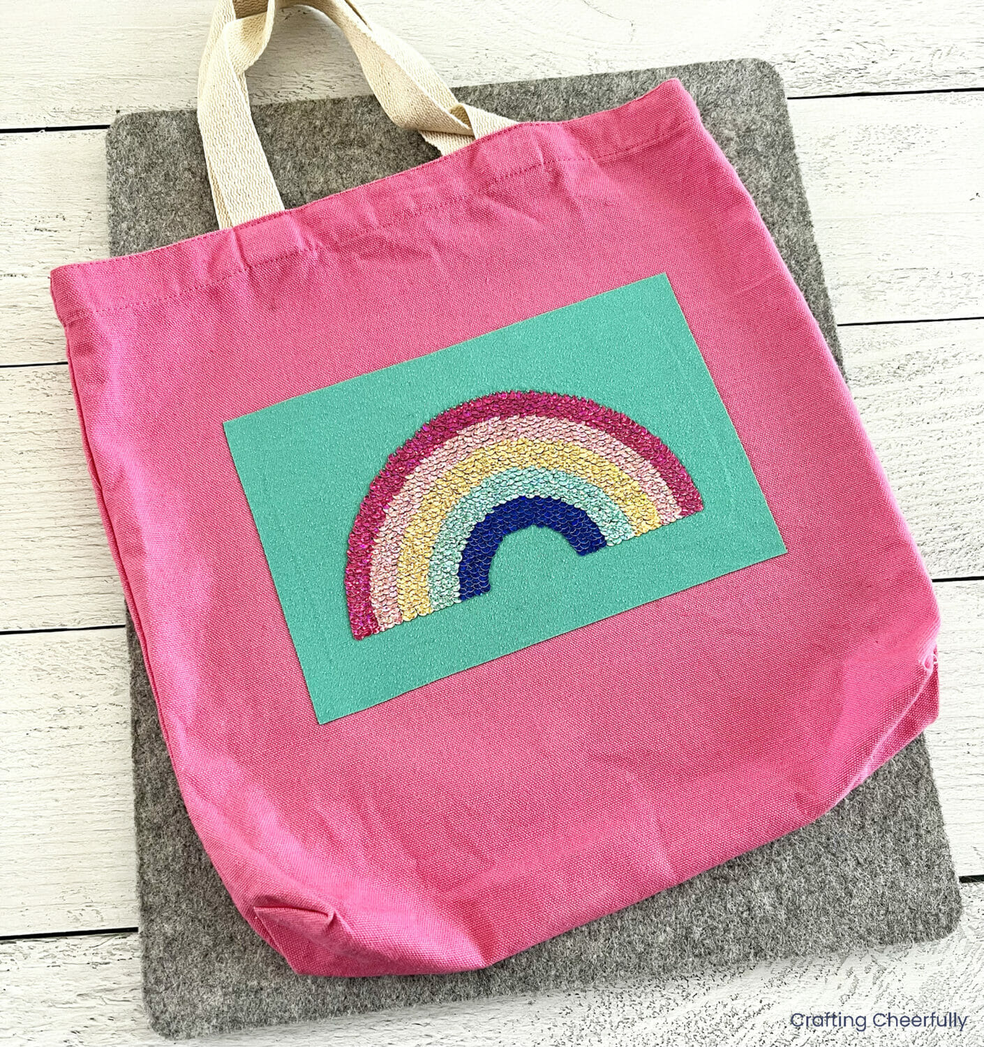 A pink tote bag decorated with a sequin rainbow from a used t-shirt.