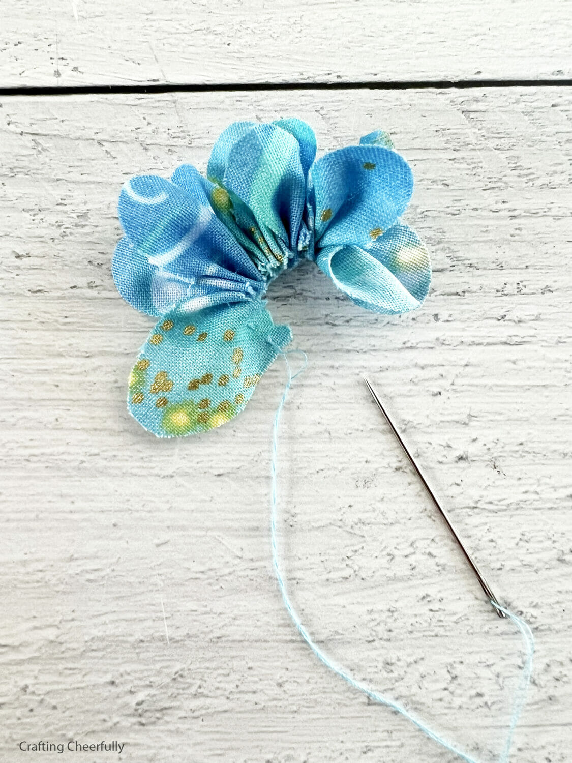 The thread along the edge is gathered forming a tight flower shape.