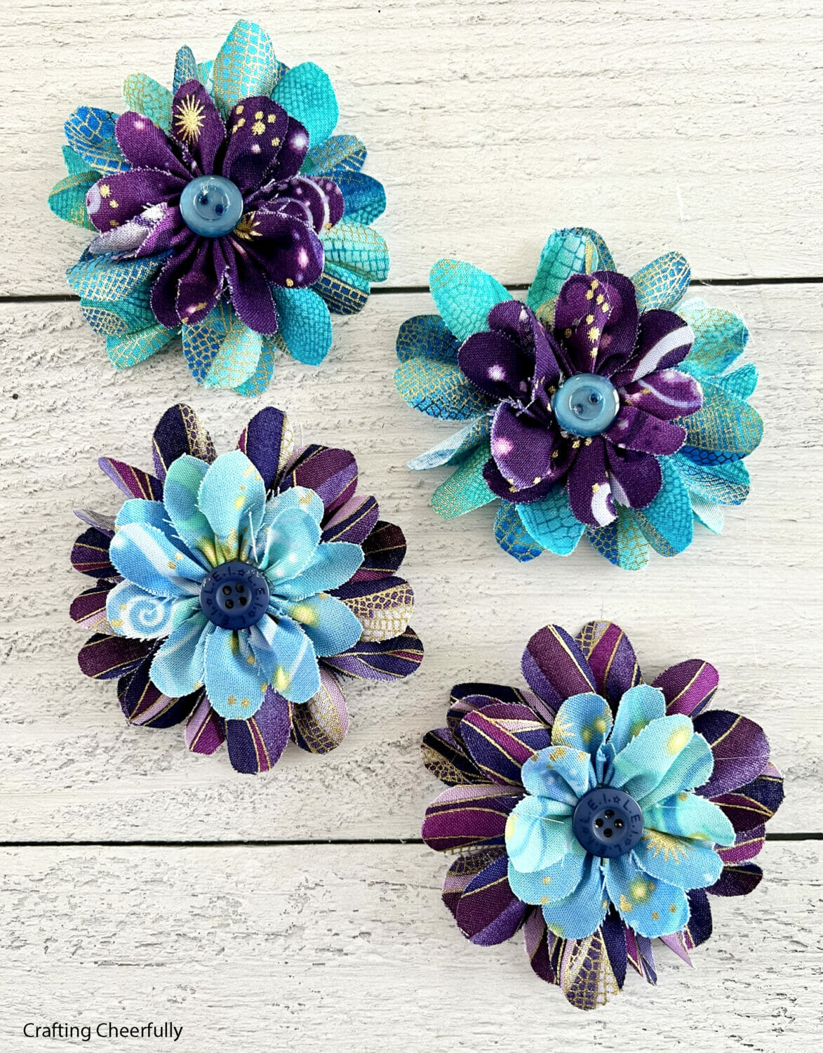 Four flowers made from stacking small fabric flowers on top of larger ones.