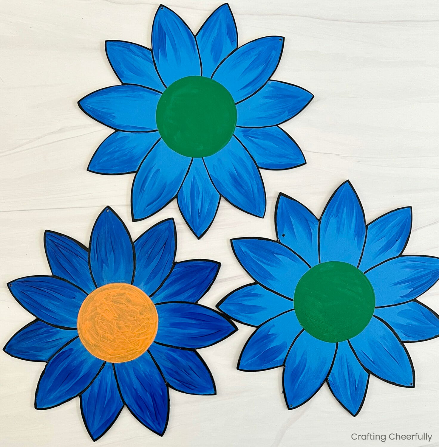 The center of each wood flower is painted with orange or green paint and the petals are outlined with black paint.