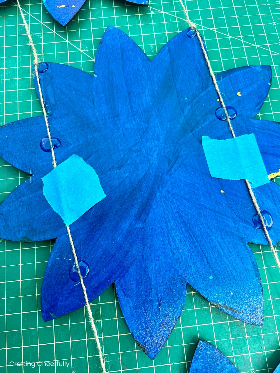 Glue is used to hold the twine in place on the back of the wood flowers.