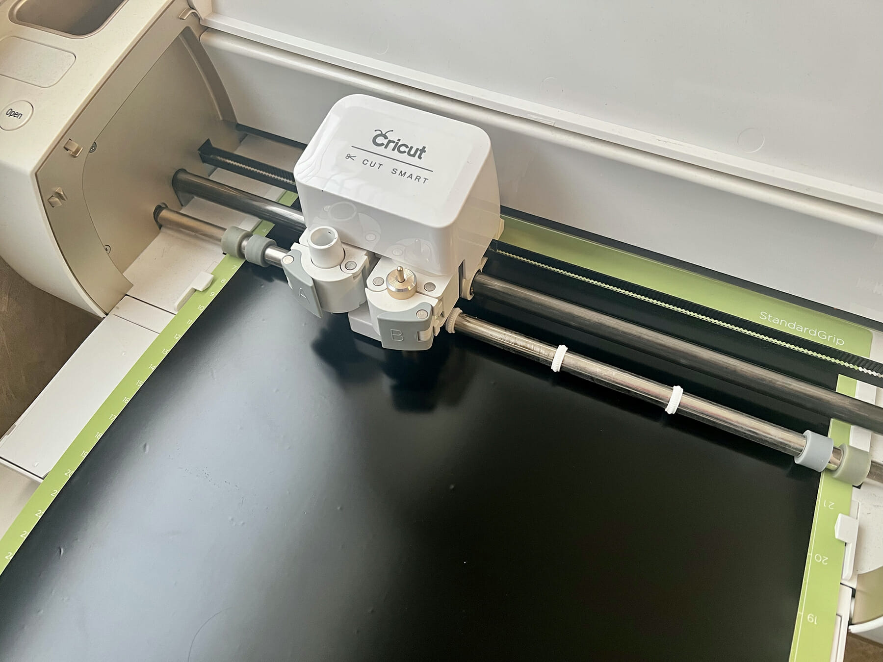 Cricut cutting machine cutting out a design from black vinyl.