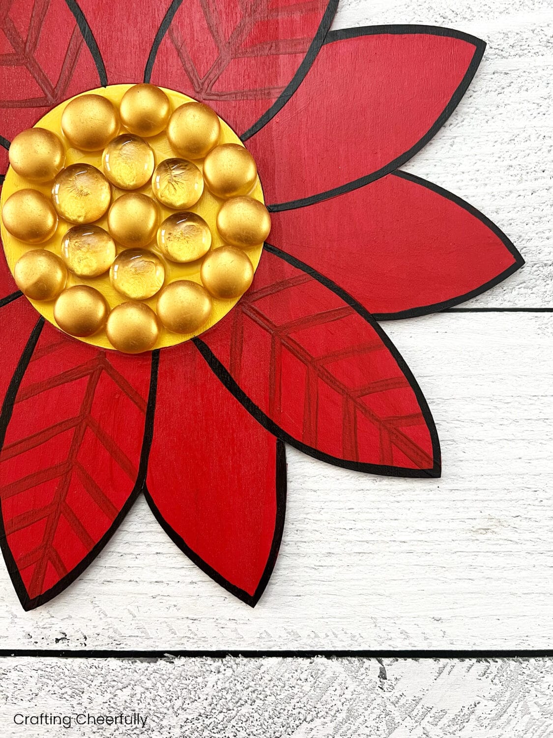 Gold gems are adhered to the center of the wooden poinsettia.