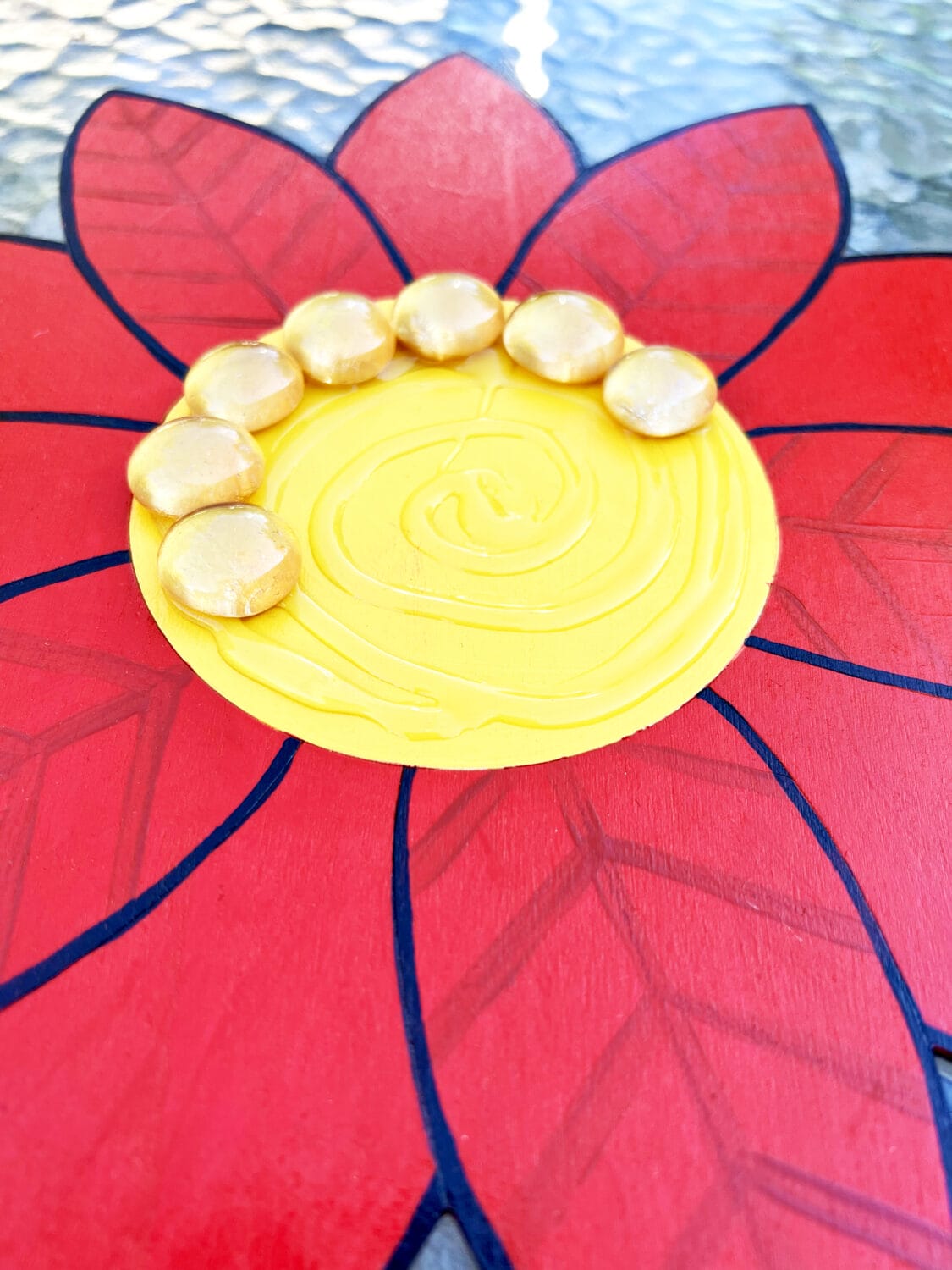 Gold gemstones are adhered to the wooden flower in circles.