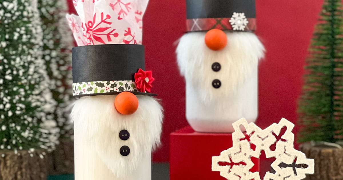 White painted mason jar decorated as a snowman gnome with a faux fur beard, paper hat and small carrot nose