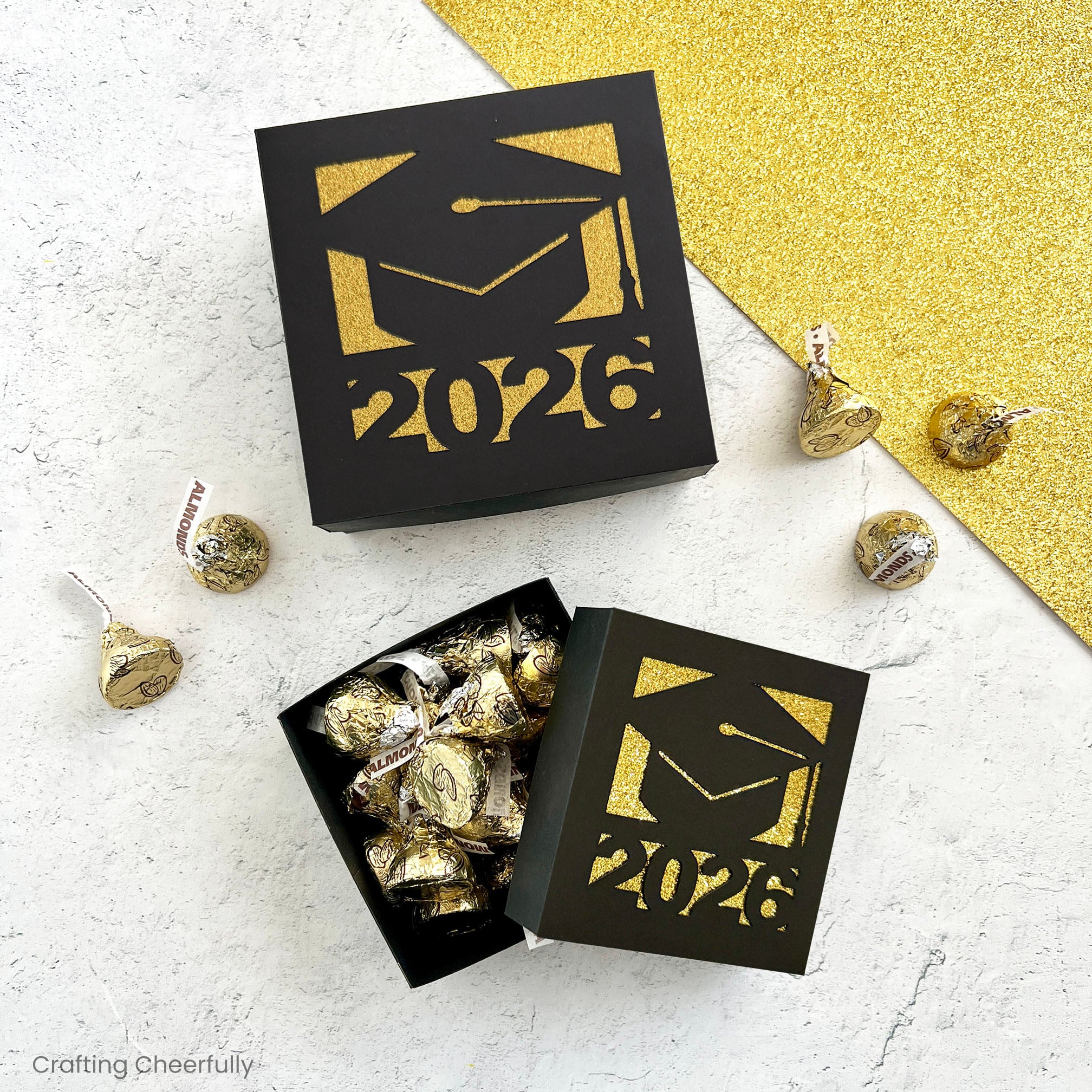 Graduation gift boxes made with black and gold cardstock are filled with candy.