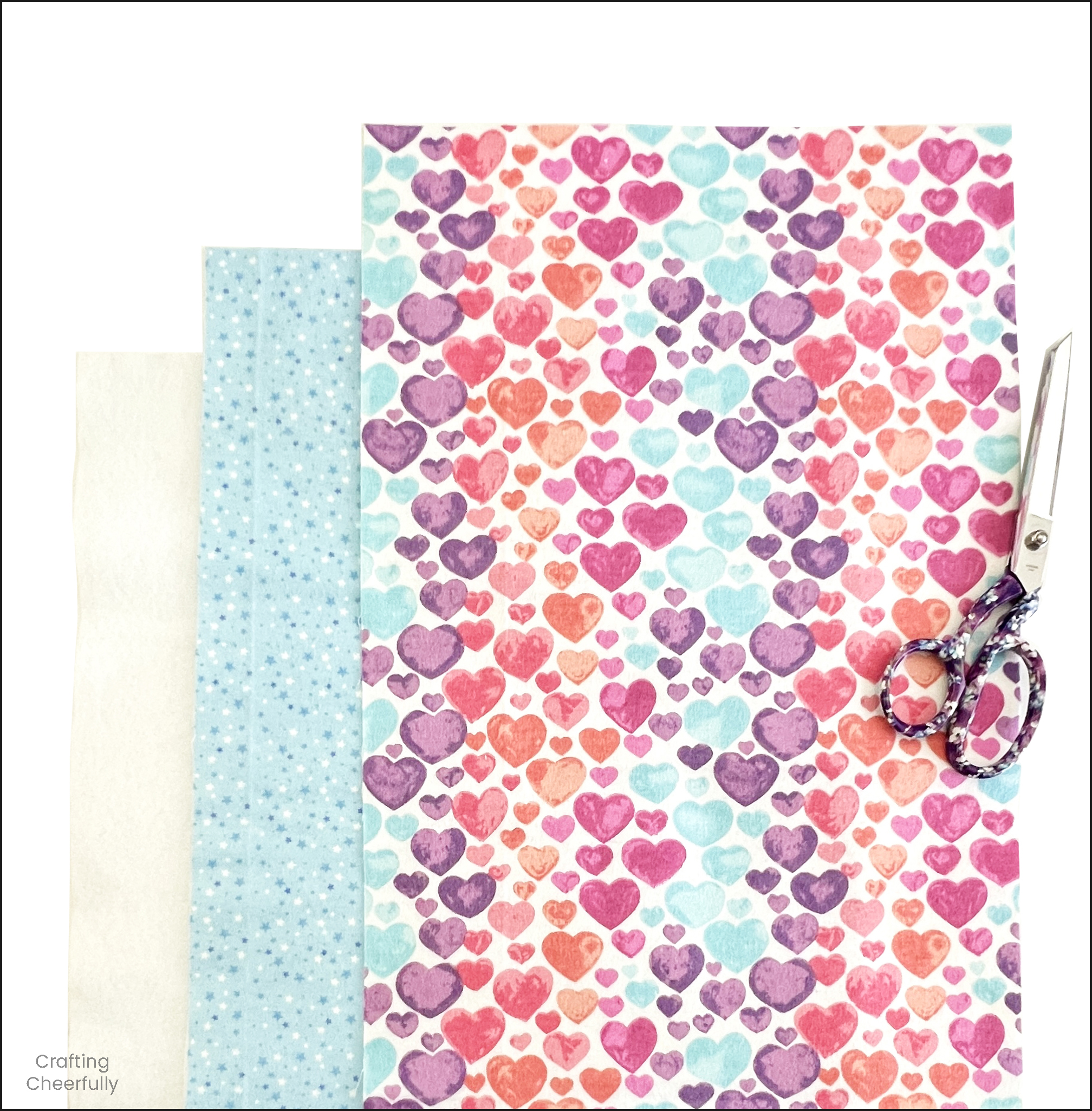 Two layers of fabric and a layer of interfacing lay with a fabric scissors.