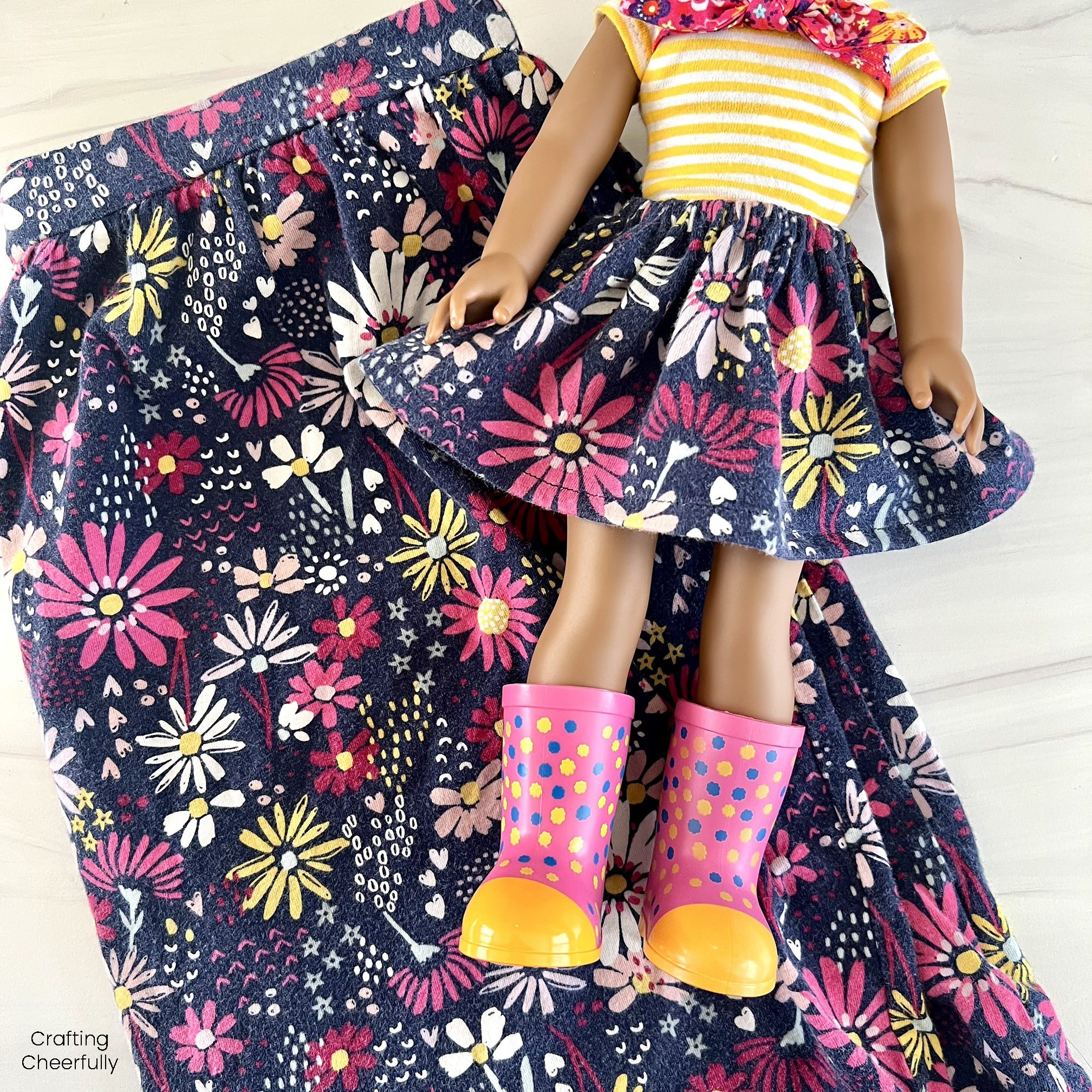 Doll wearing cute floral skirt lays on top of a folded skirt. 