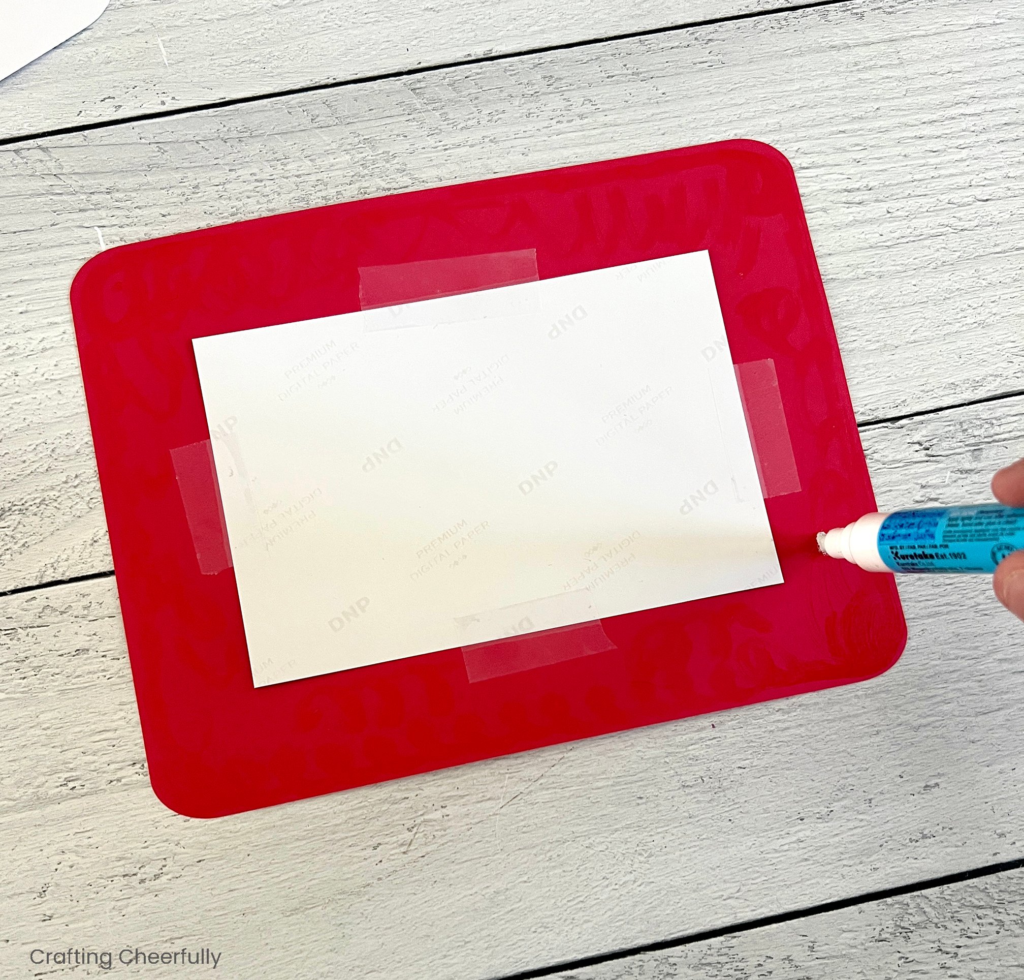 The photo is taped to the back of the frame and a glue pen is used to add adhesive to the back of the frame.
