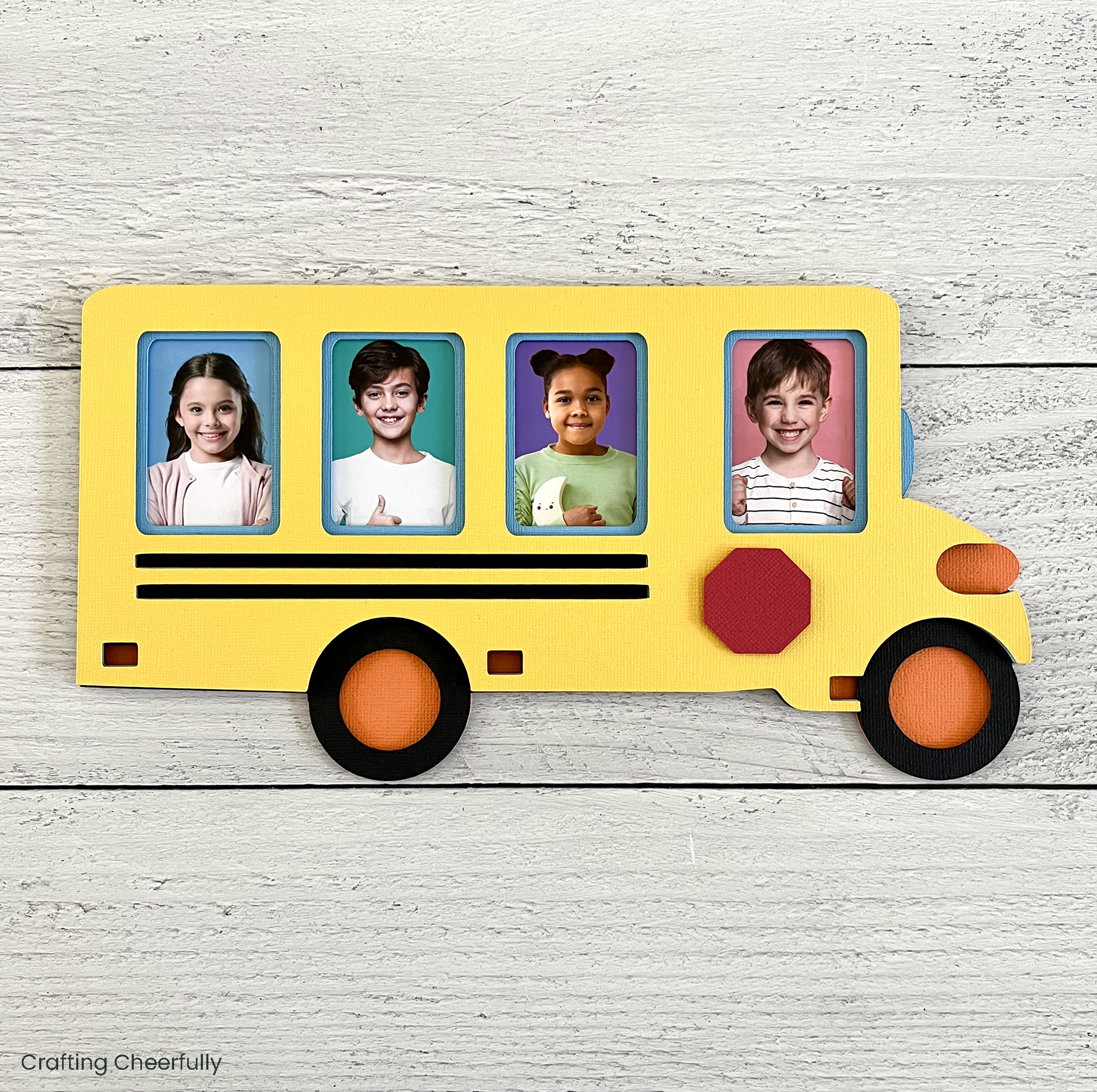 Layered paper school bus frame with pictures of four kids inside the frame.
