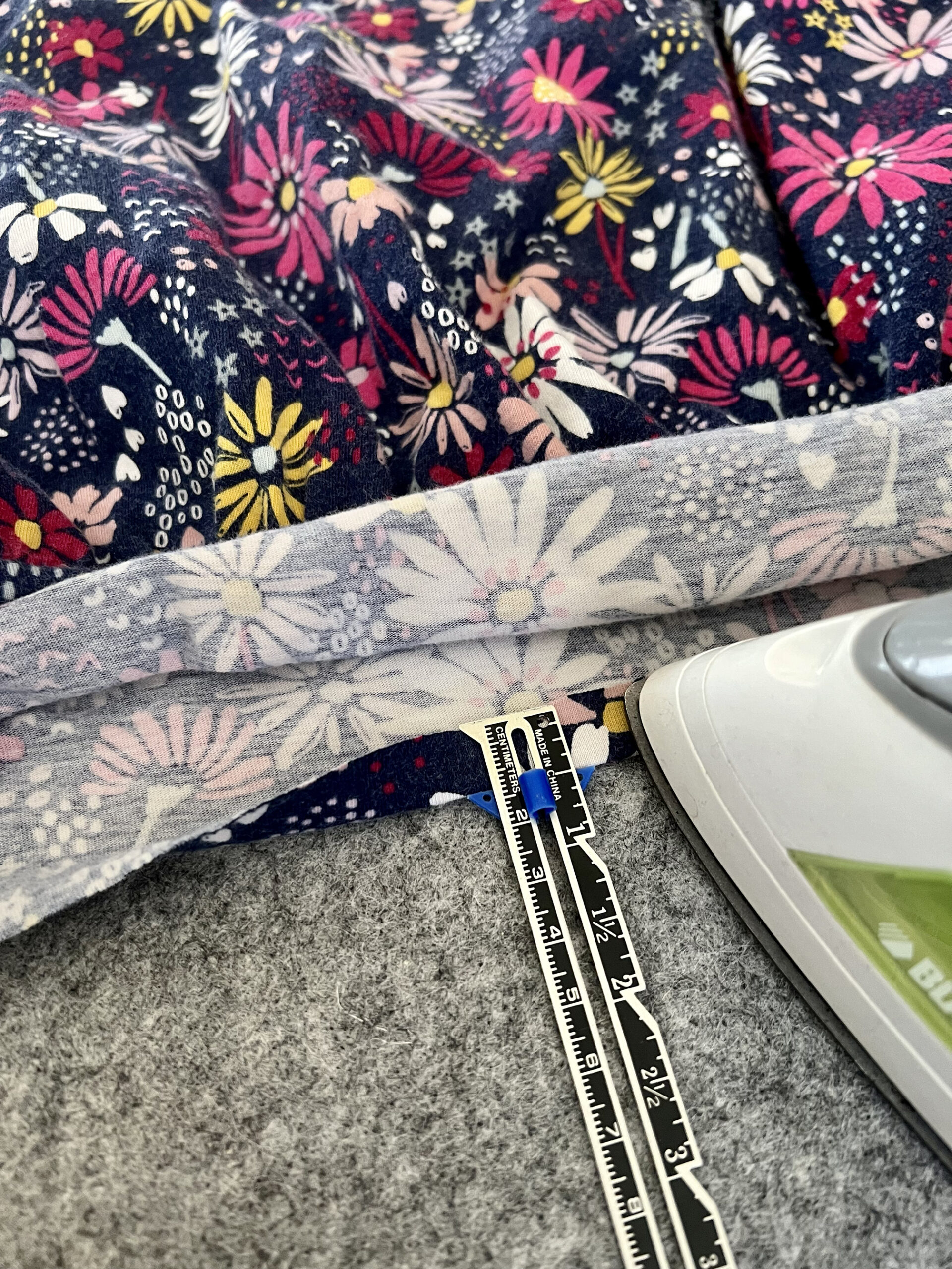 A quarter inch of fabric is pressed using a seam gauge to help measure.