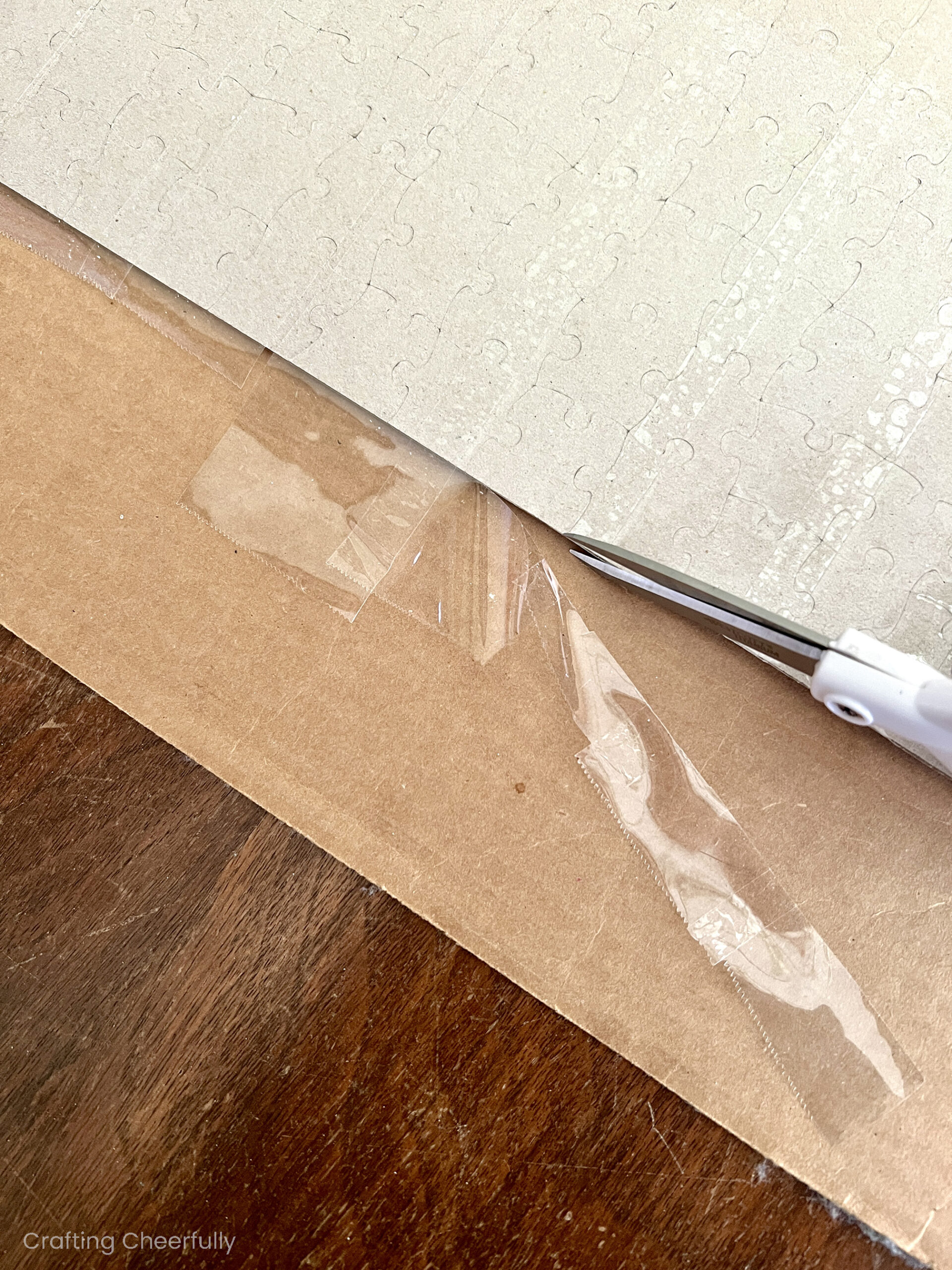 A sharp scissors is used to trip tape that extends beyond the puzzle.