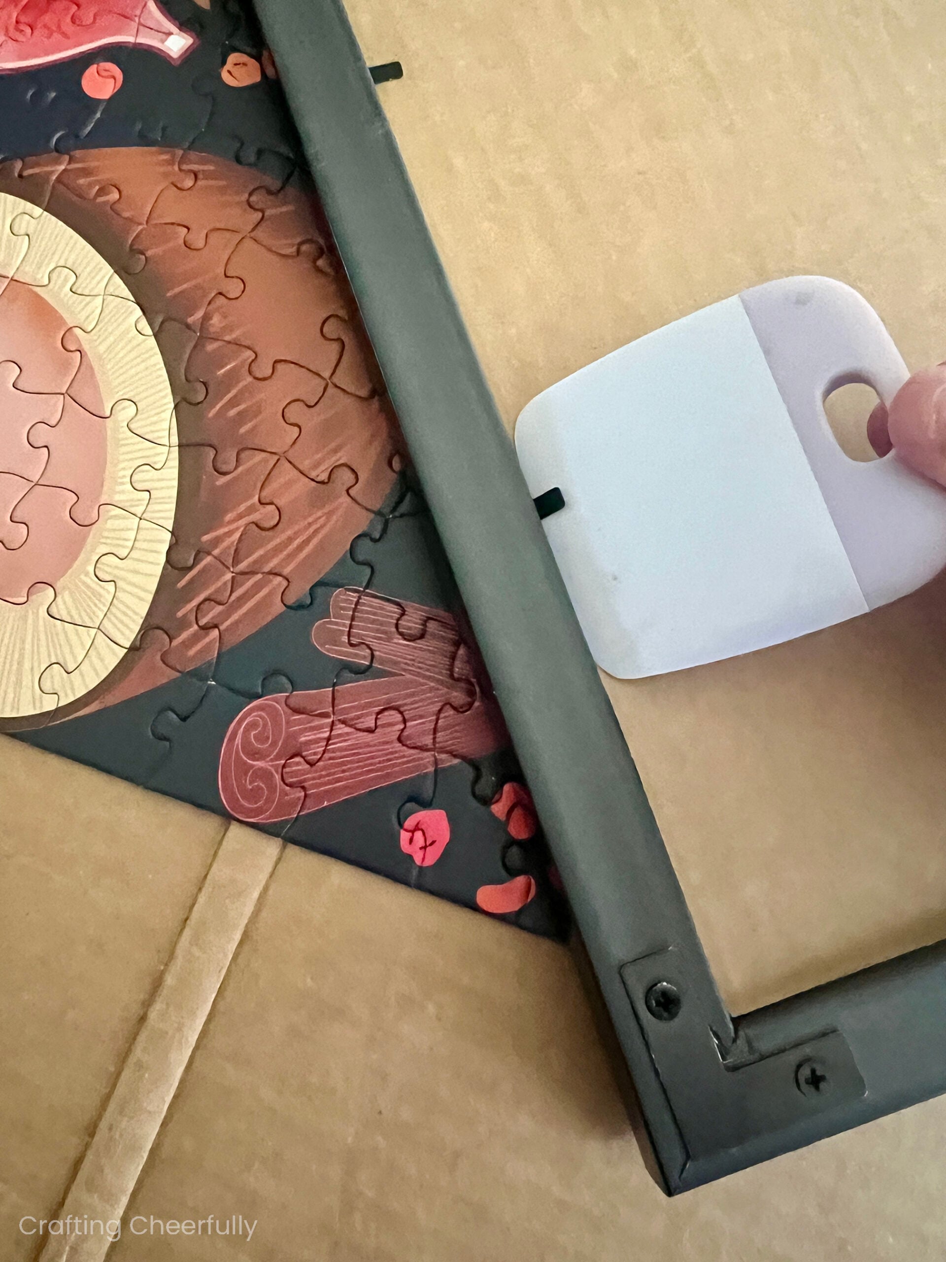 A Cricut smoothing tool is used to lift up the metal tabs on the back of the frame.