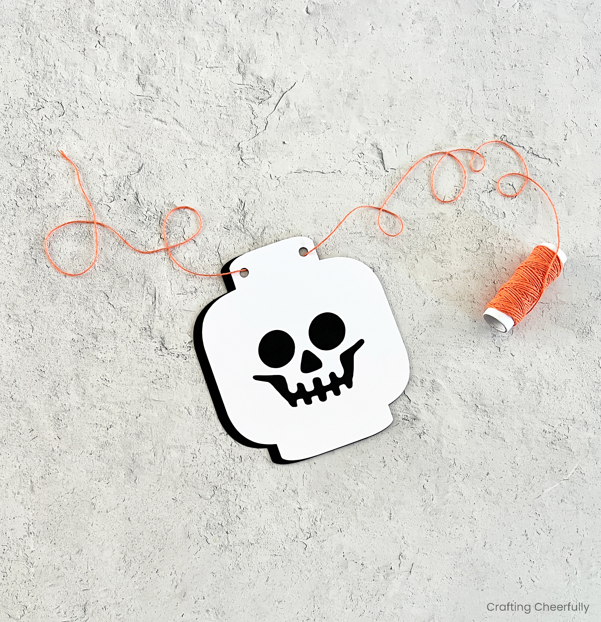 Orange twine laced through the top holes in the skeleton head.