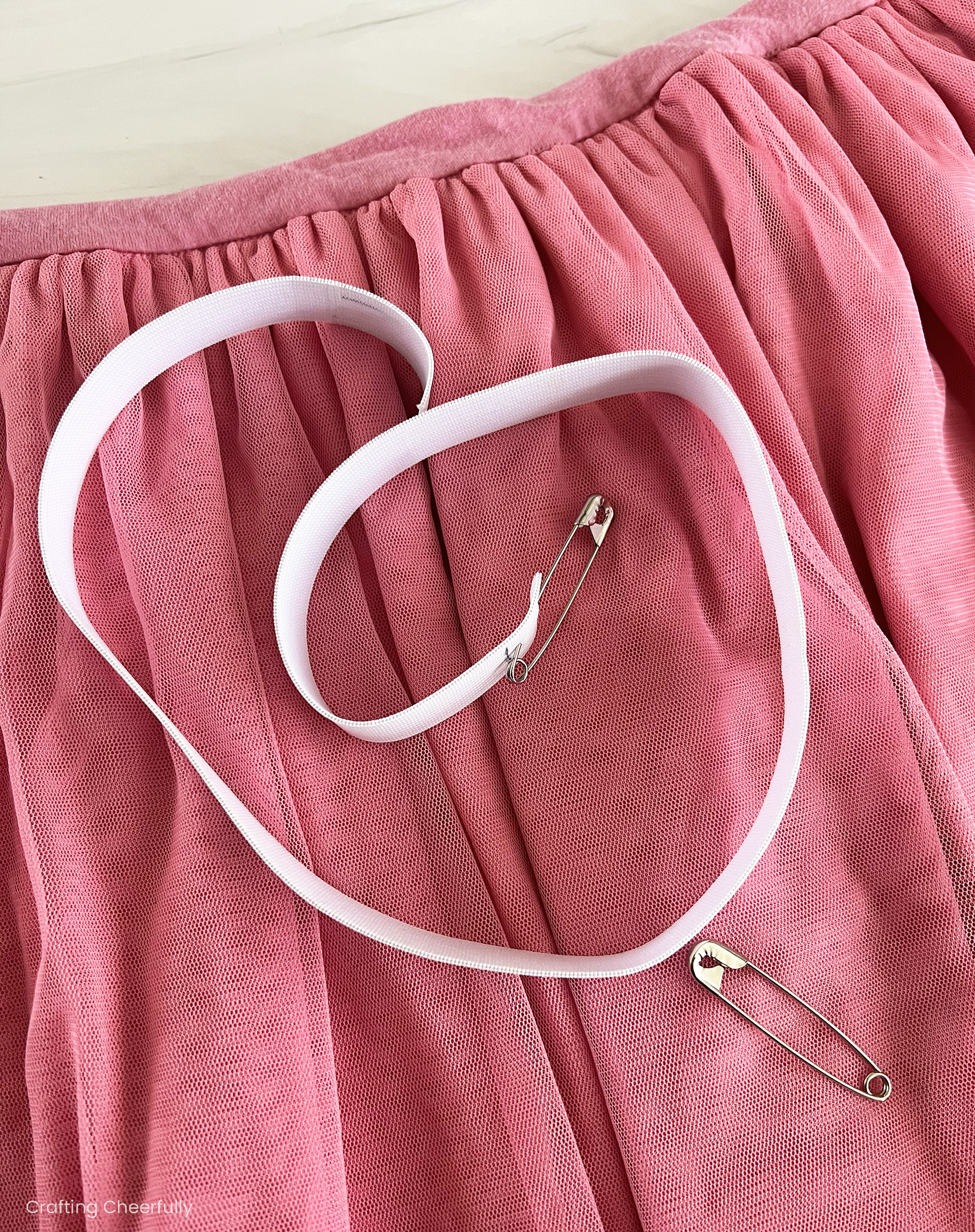 A piece of elastic lays on top of the skirt with a safety pin attached to one end.