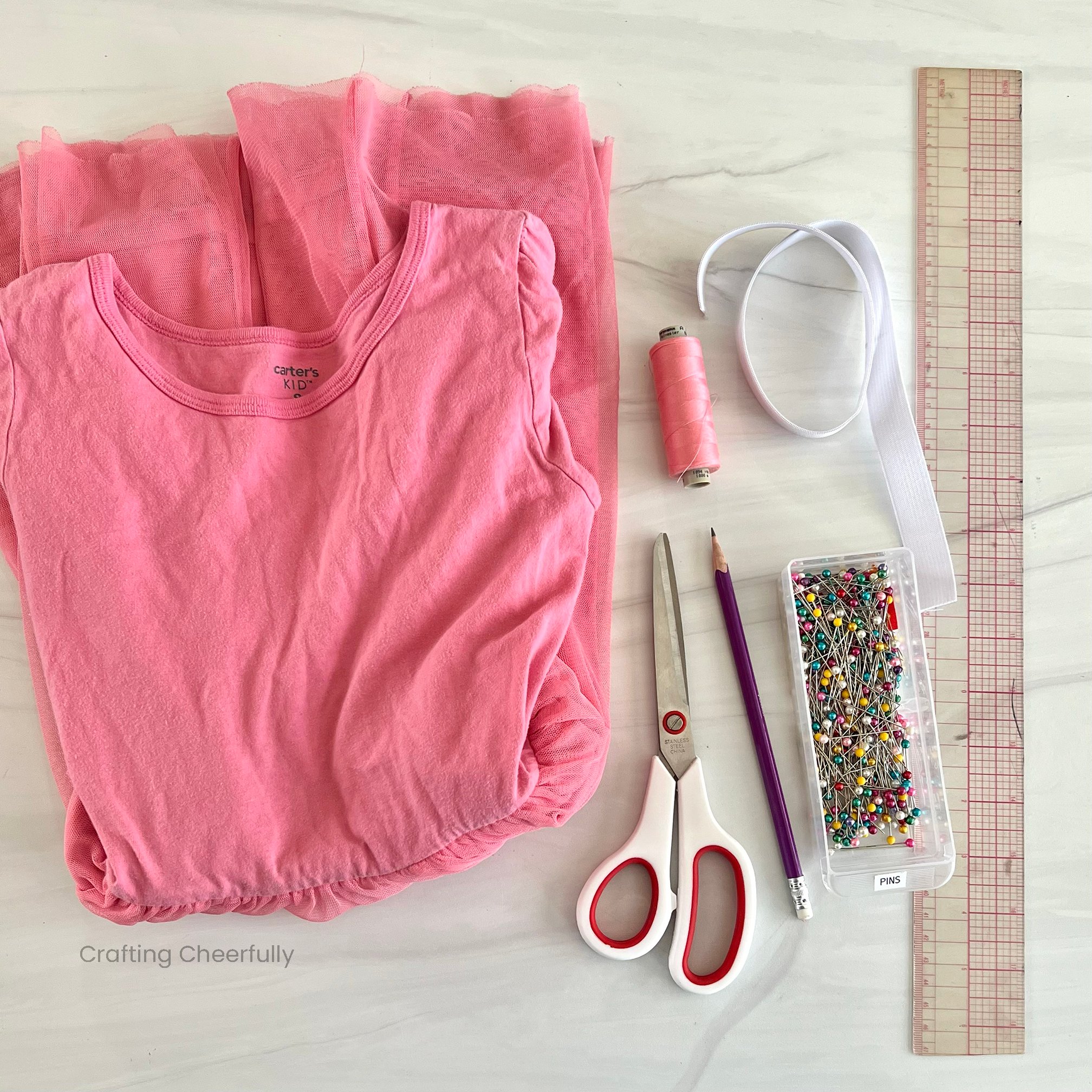 Supplies needed including dress, thread, pins, elastic, ruler and scissors lay on a table.