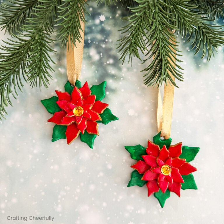 Air-Dry clay poinsettia ornaments hang from evergreen branches.