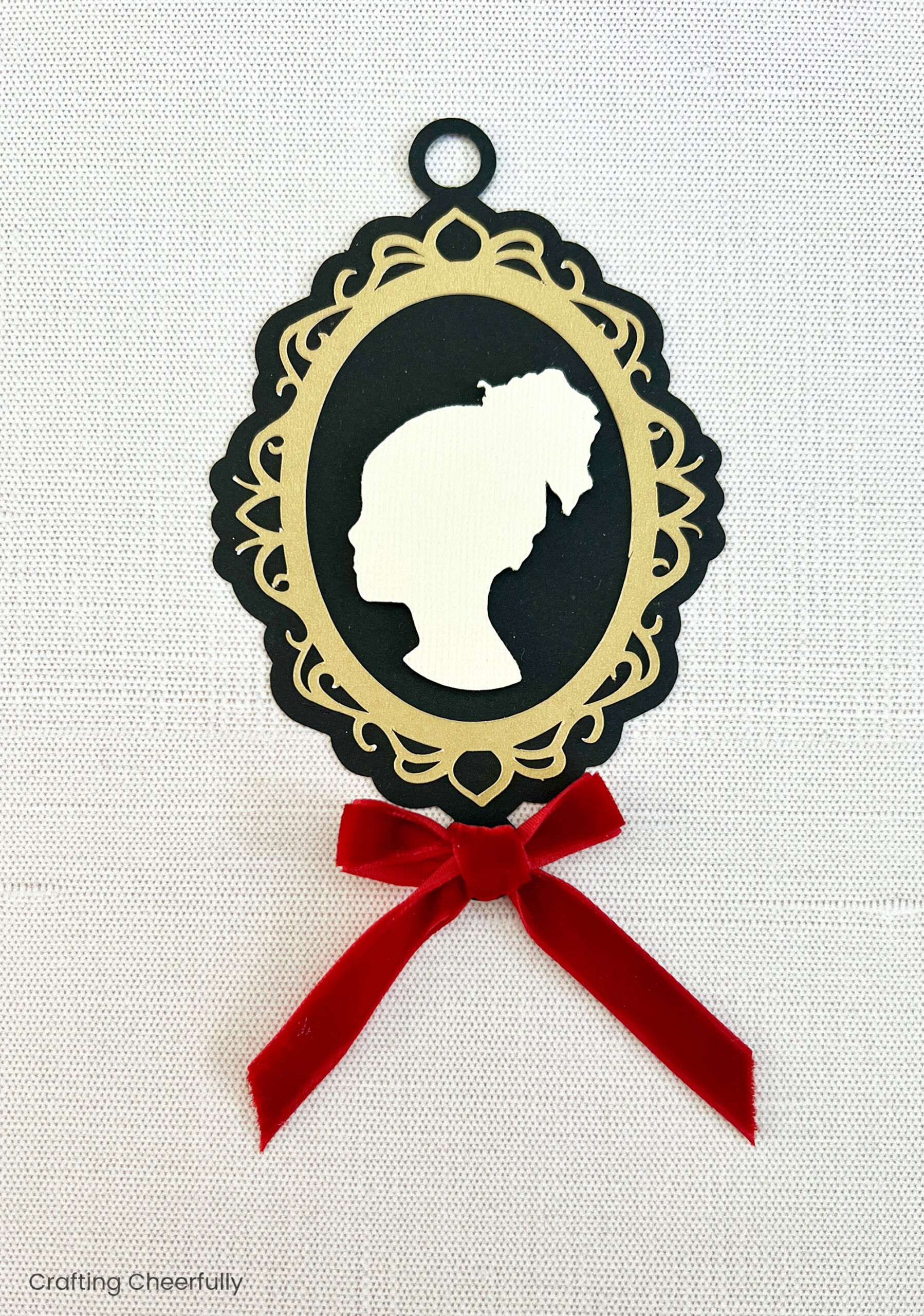 Red velvet bow is added to the bottom of the cameo ornament.
