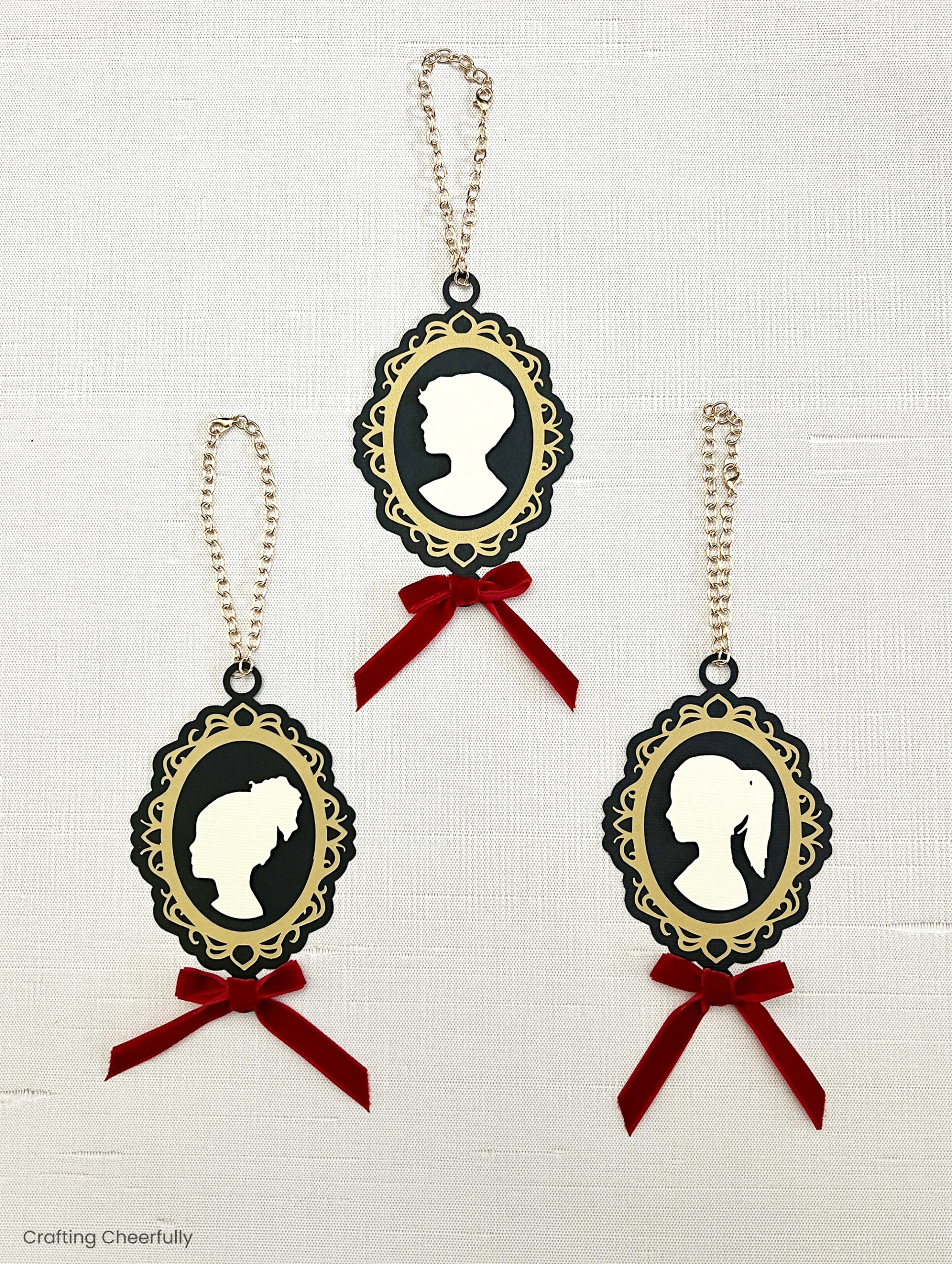 Three cameo ornaments with gold chain hanging loops.