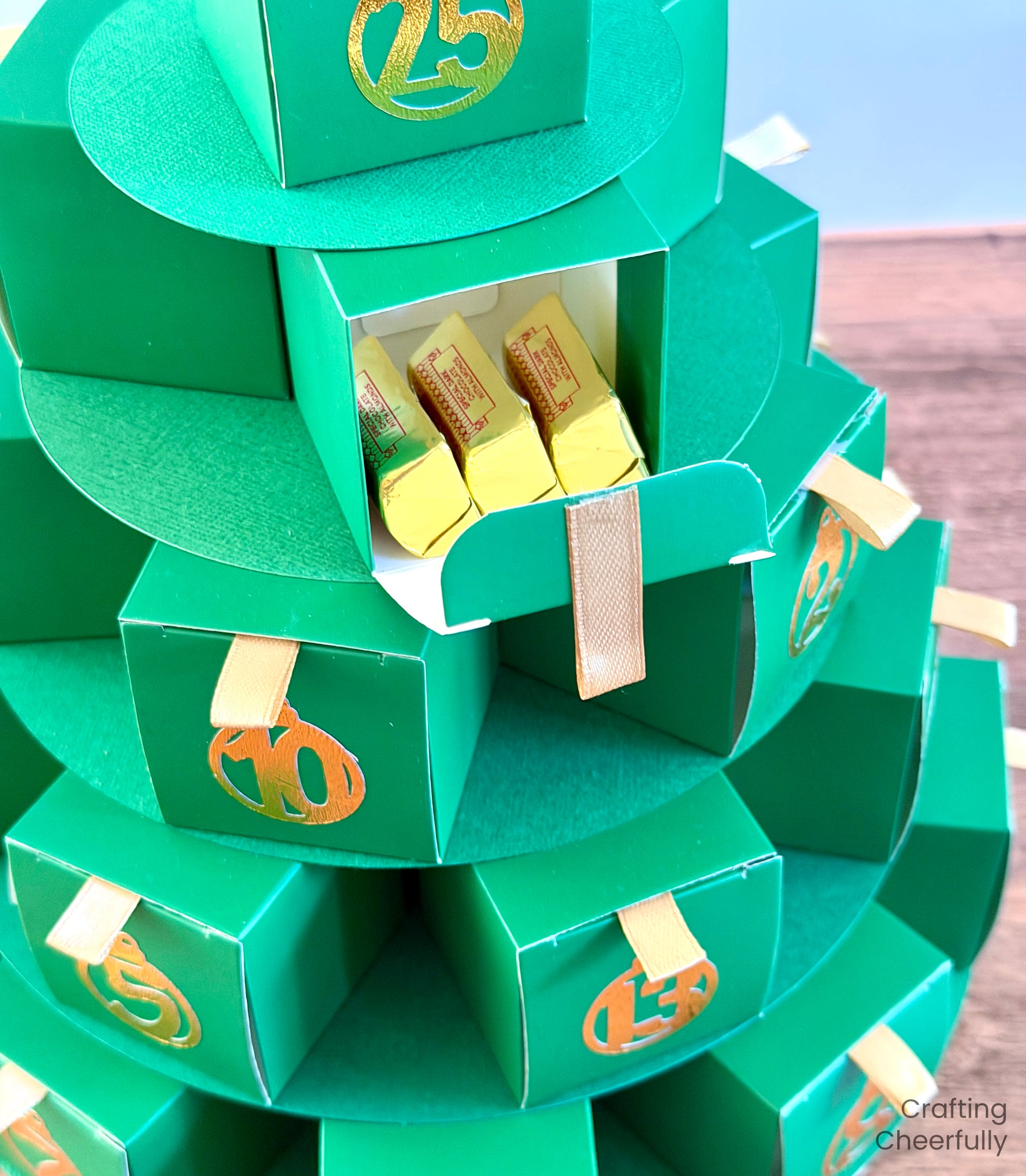 One of the small boxes on the Advent Calendar Christmas tree is opened showing gold chocolates.