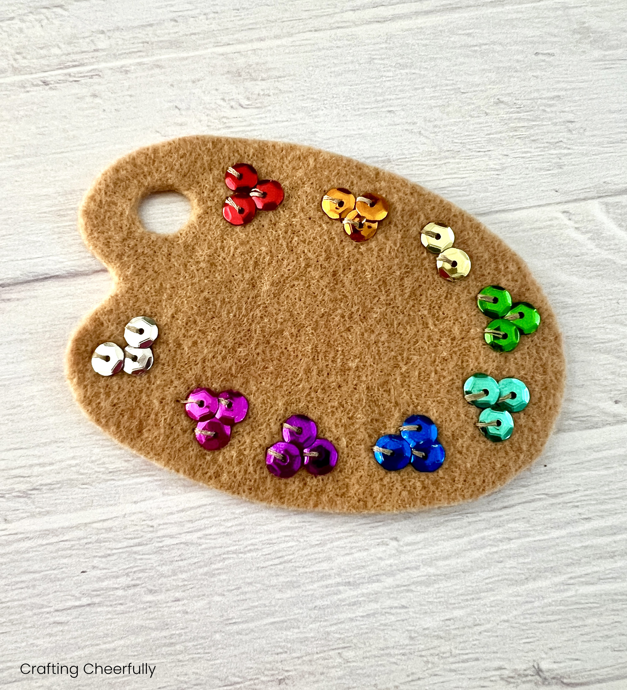 Tan felt paint palette with colorful sequins.