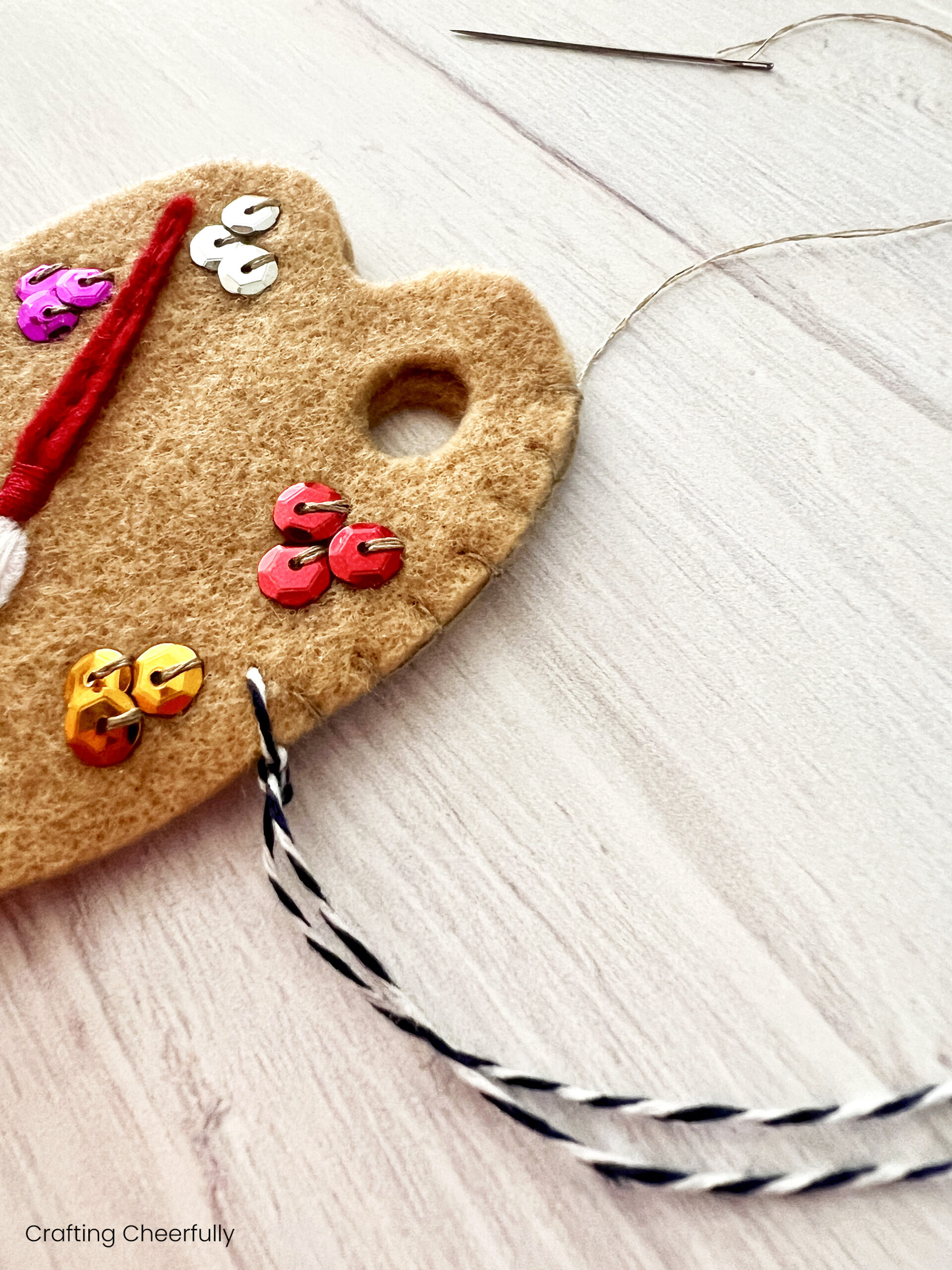 A blanket stitch is used to stitch the two pieces of felt together around the edges using tan thread.