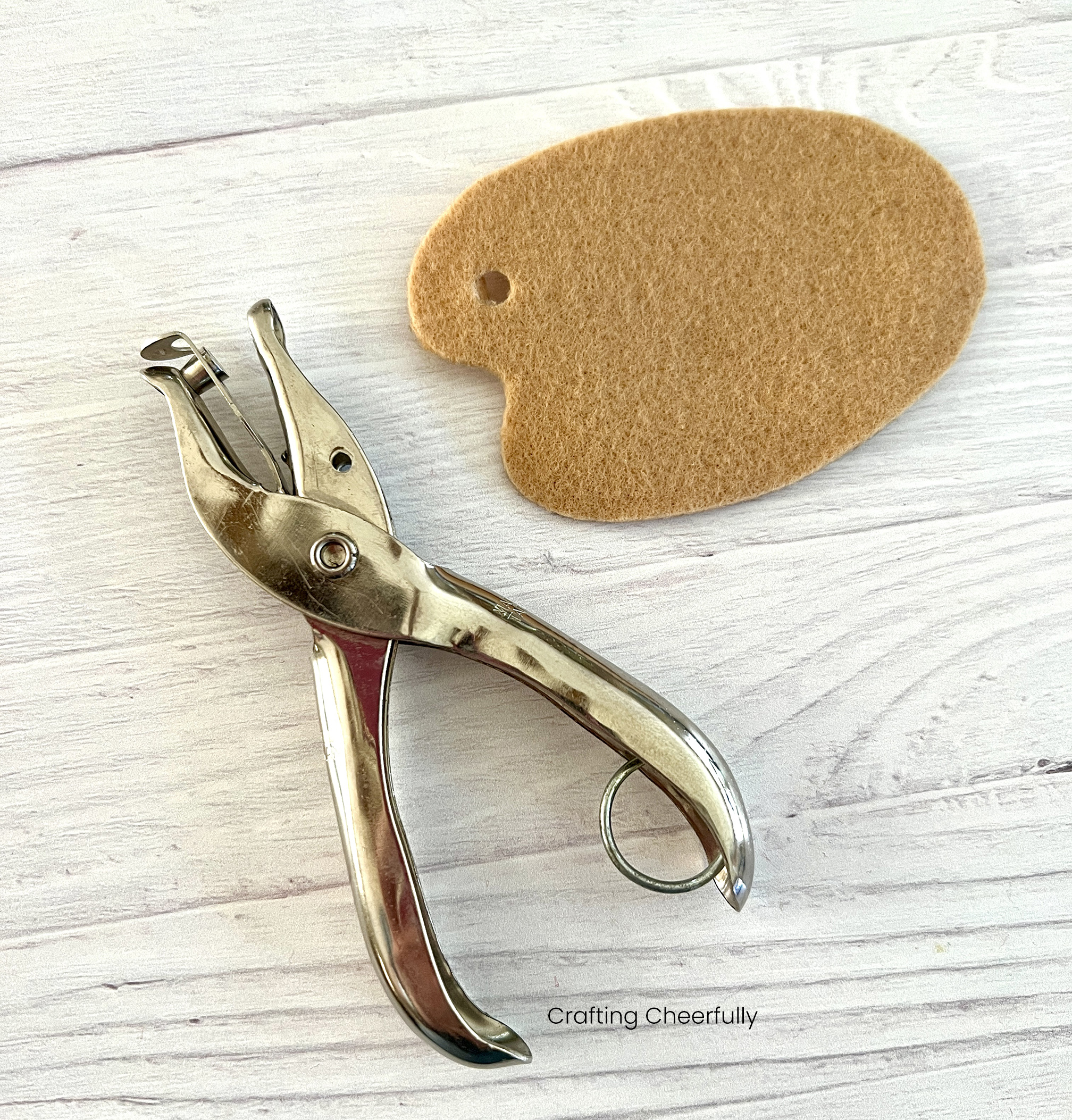 A hold punch lays next to the paint palette cut from tan felt.