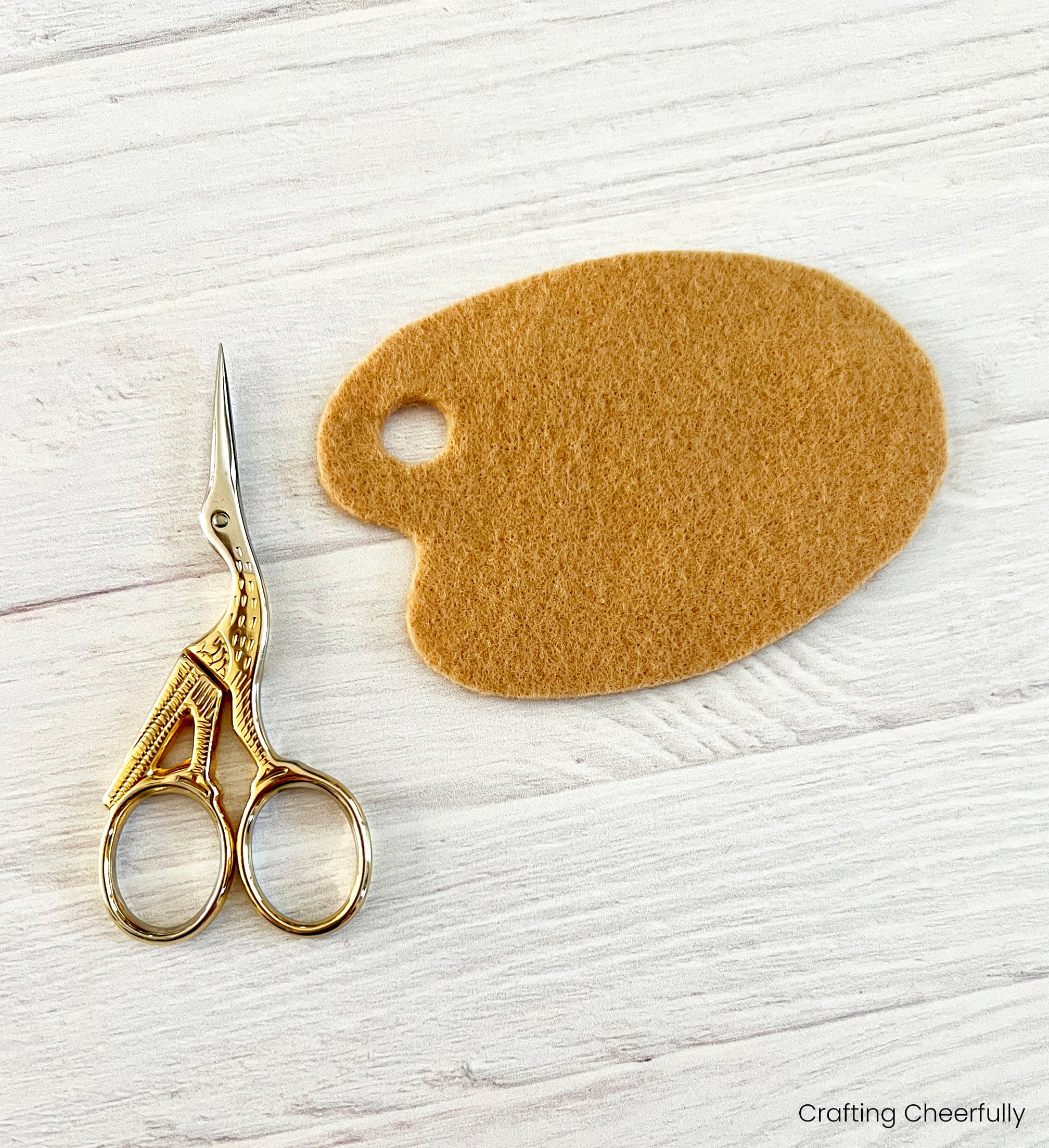 A small embroidery scissors lays next to the paint palette.