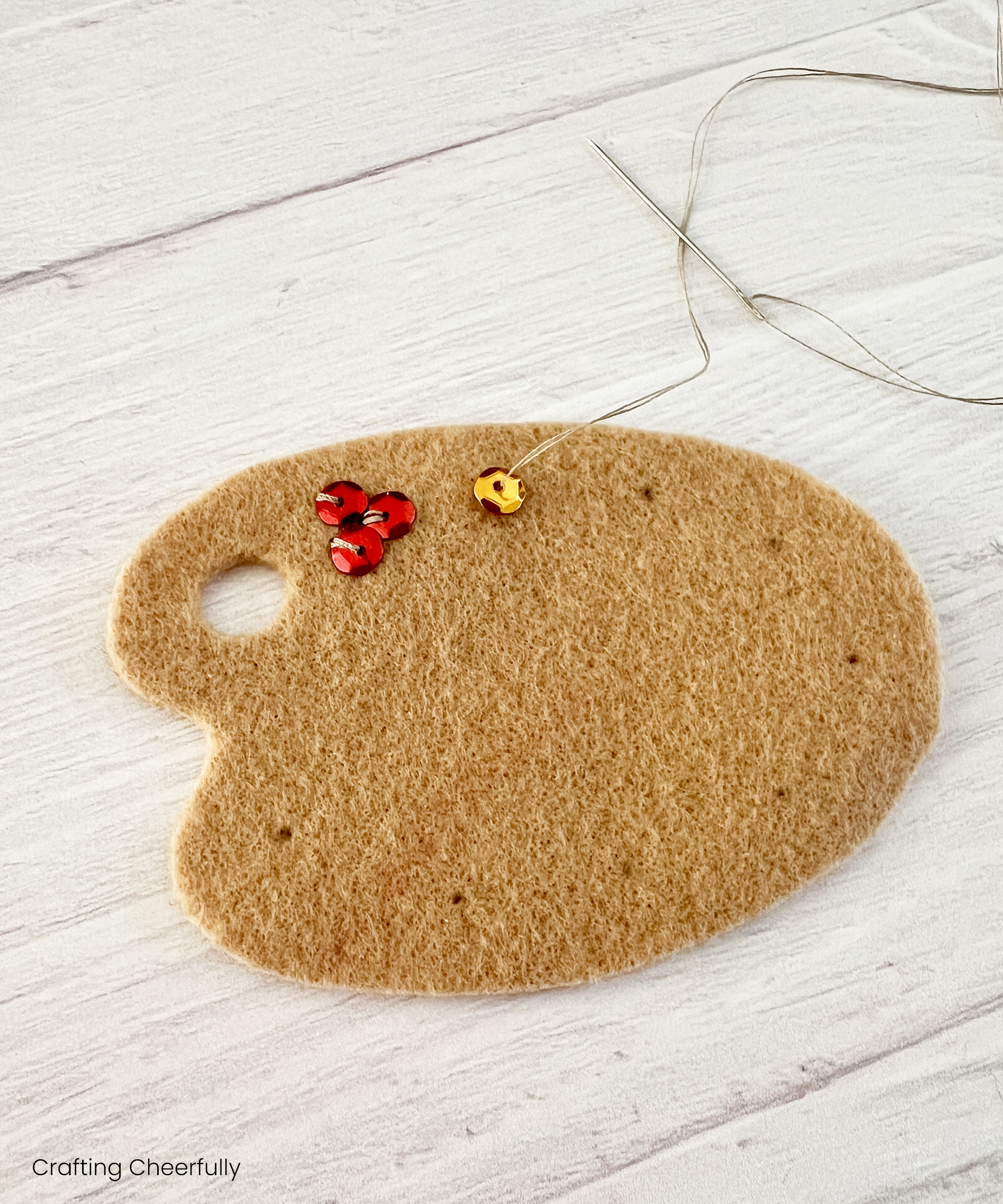 Red and orange sequins are sewn to the paint palette.