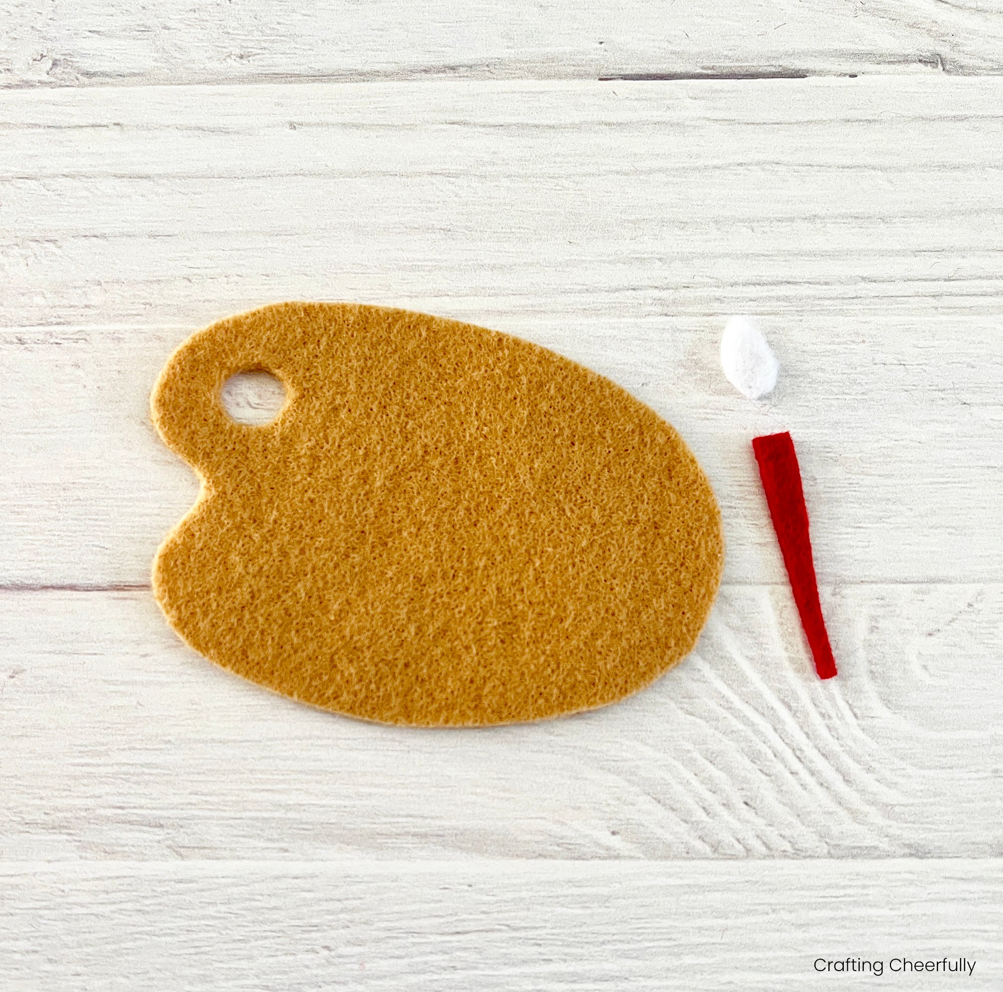 Three pieces for the ornament are cut from felt; a paint palette, paint brush handle, and brush.
