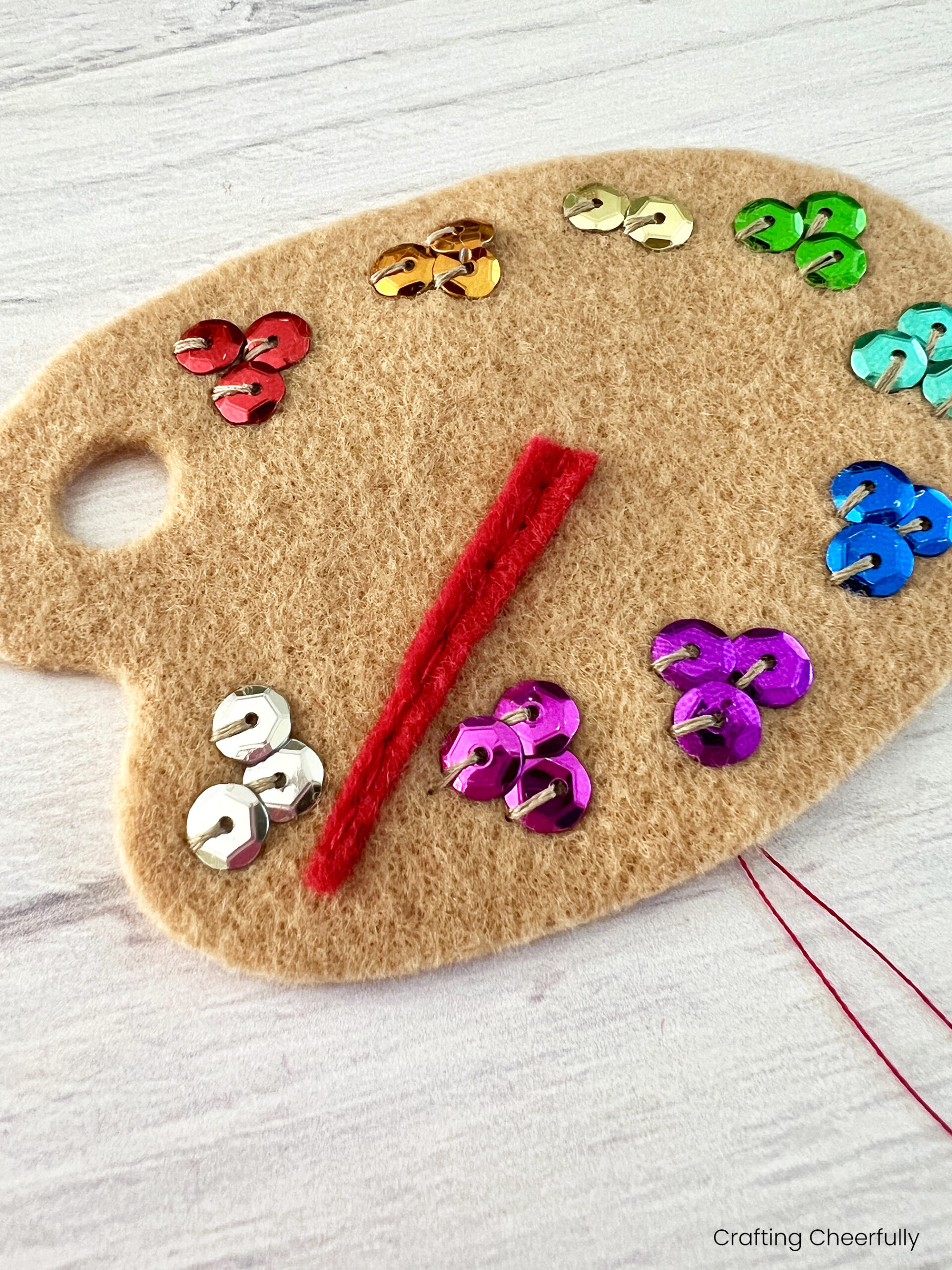 The red felt paint brush handle is stitched to the paint palette.