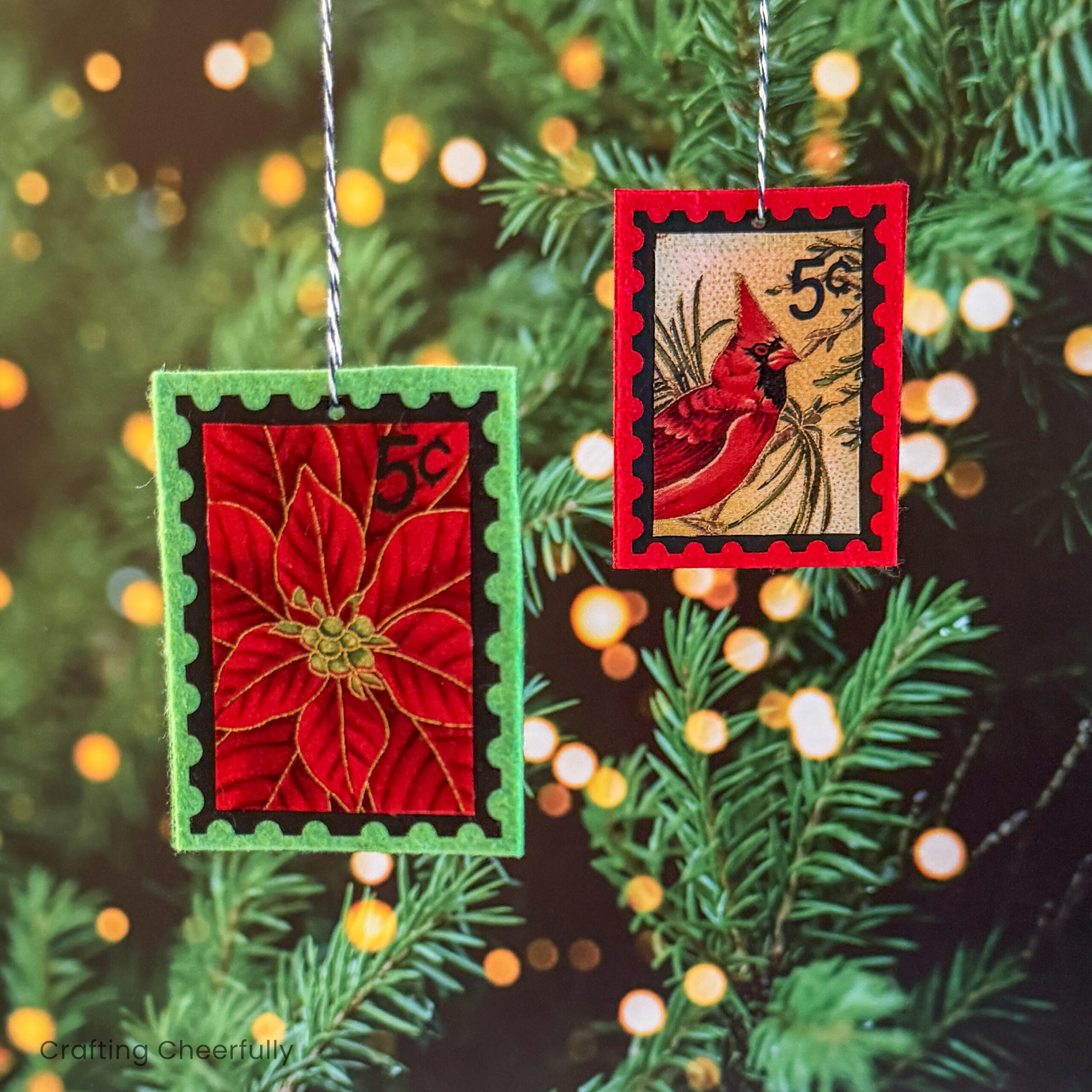 Two handmade felt postage stamp ornaments hang in a Christmas tree.