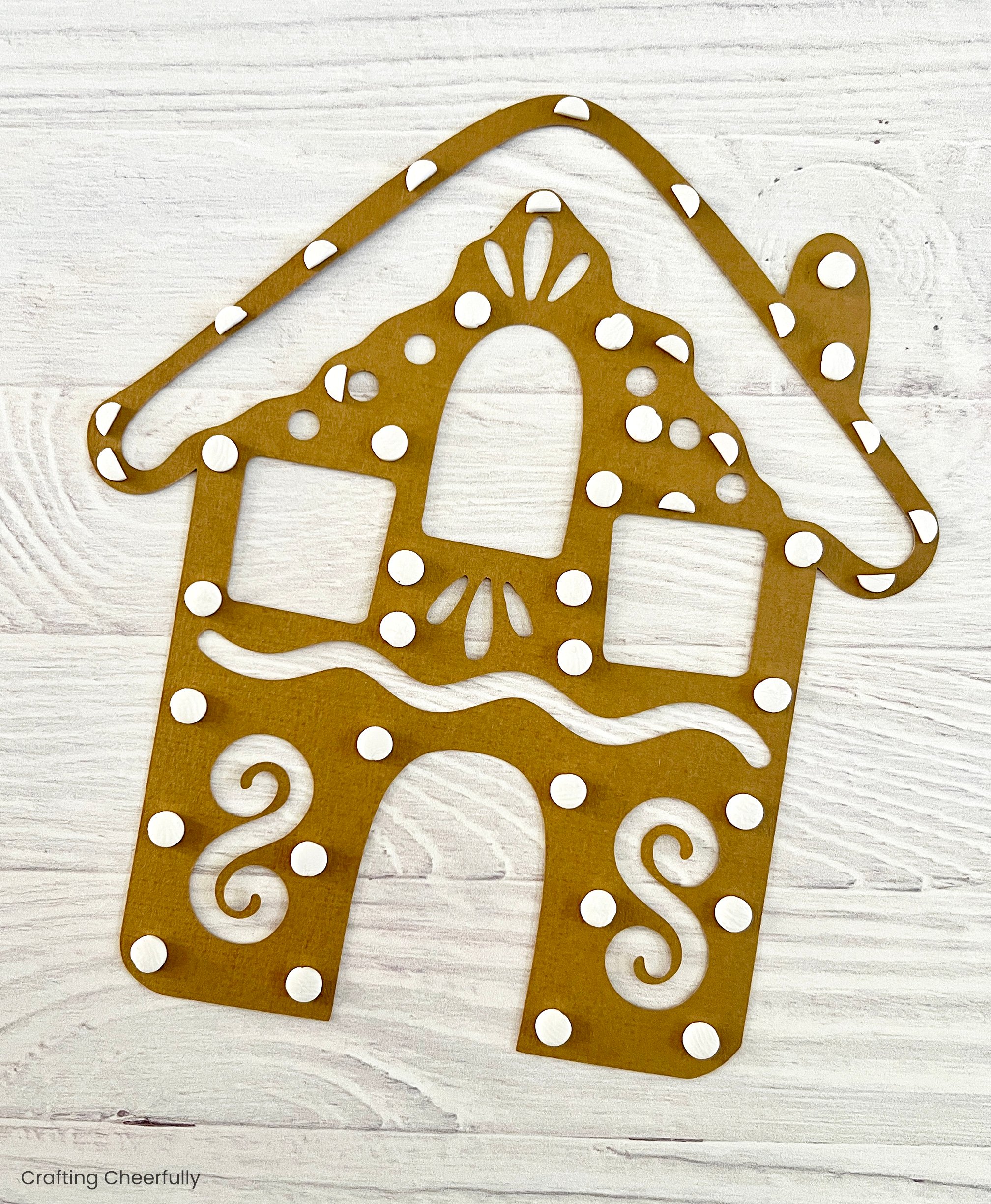 White foam dots are applied to the back of the gingerbread house.