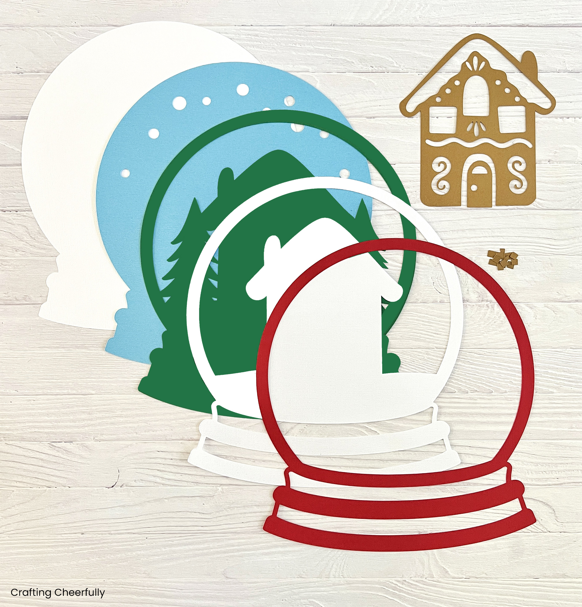 Layers of cardstock cut for the snow globe including the small gingerbread house.