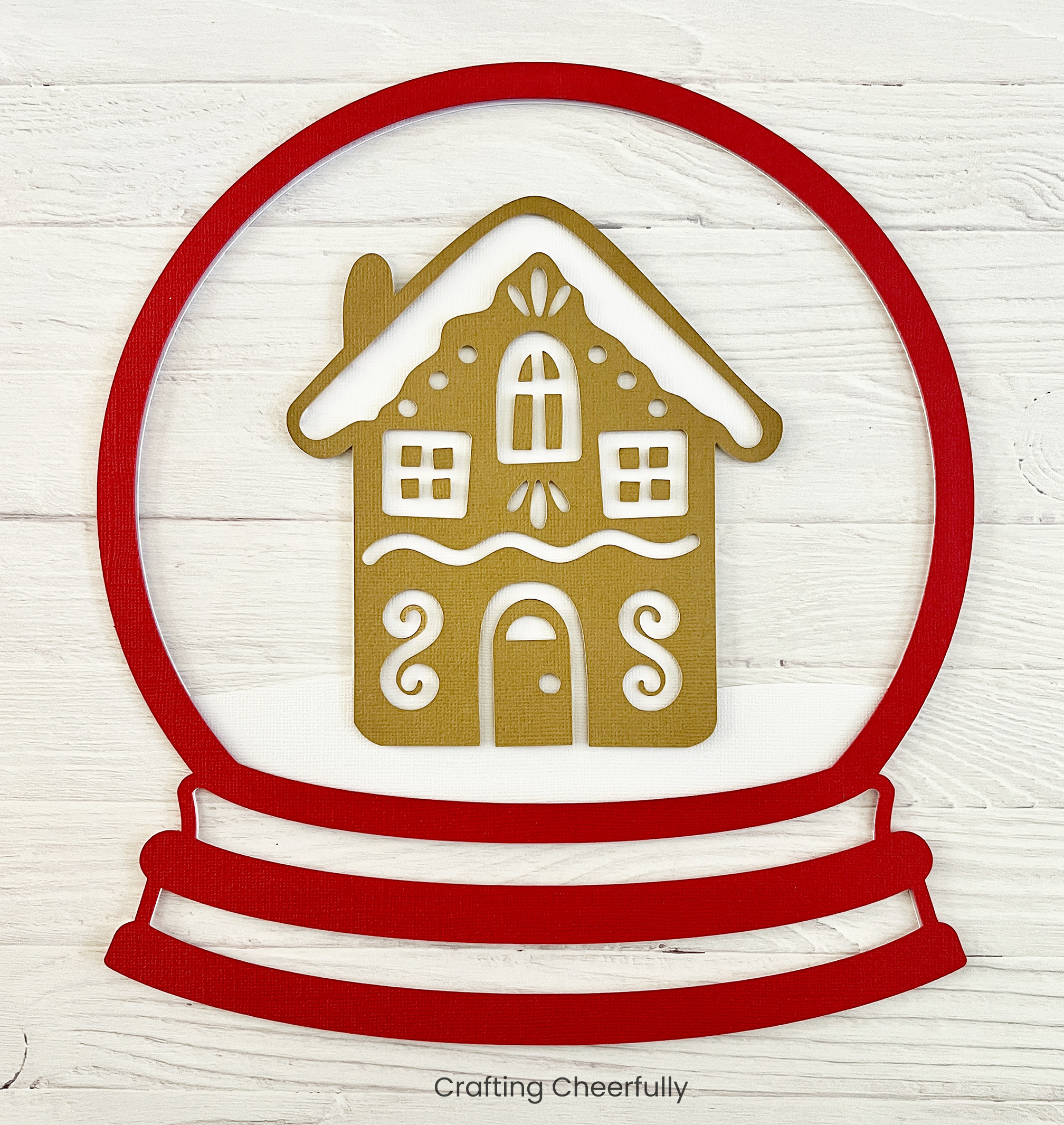 The red layer of paper is applied to the white one framing the gingerbread house.