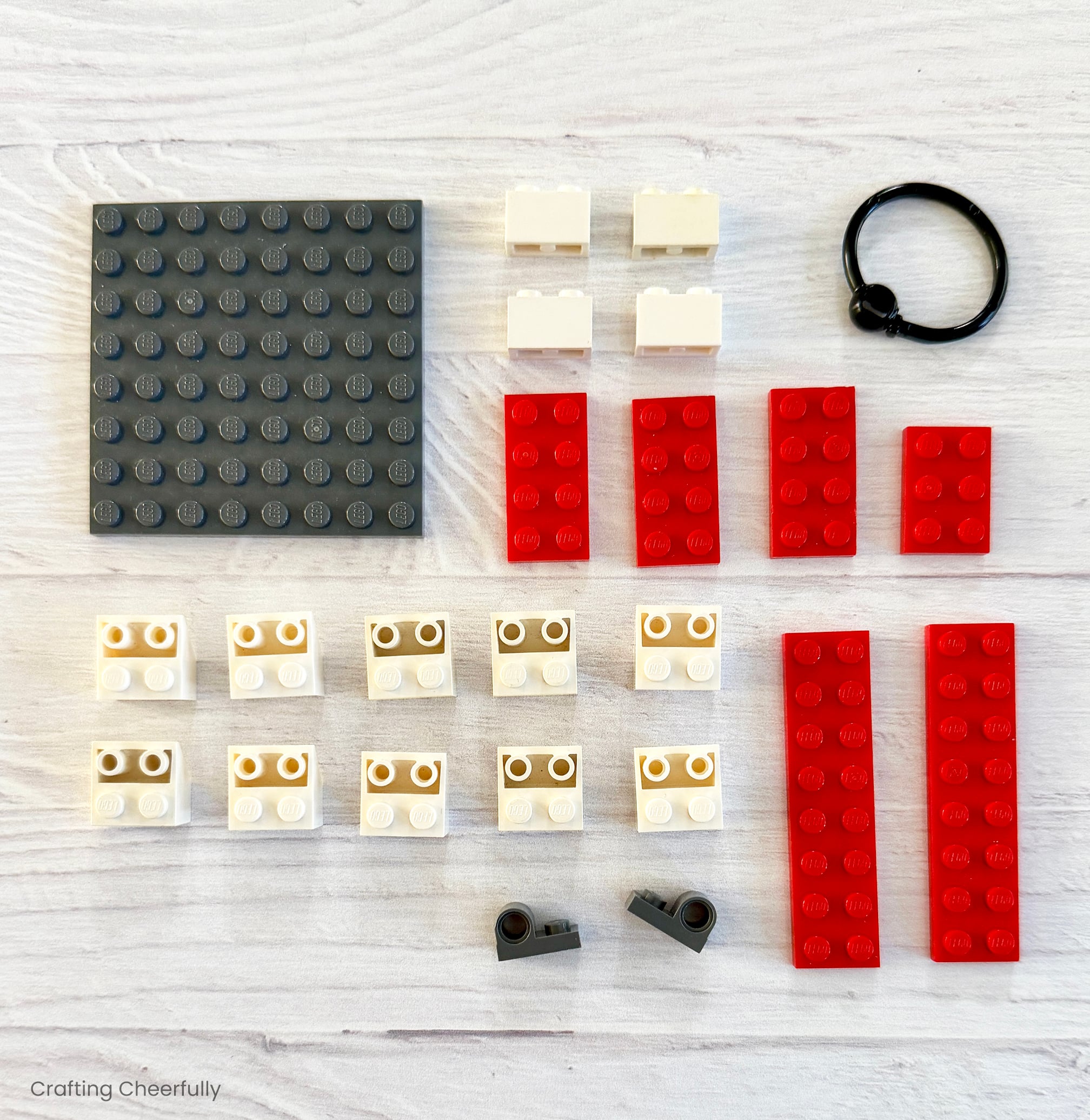 Lego pieces needed to make the ornament are arranged on a white wood surface.