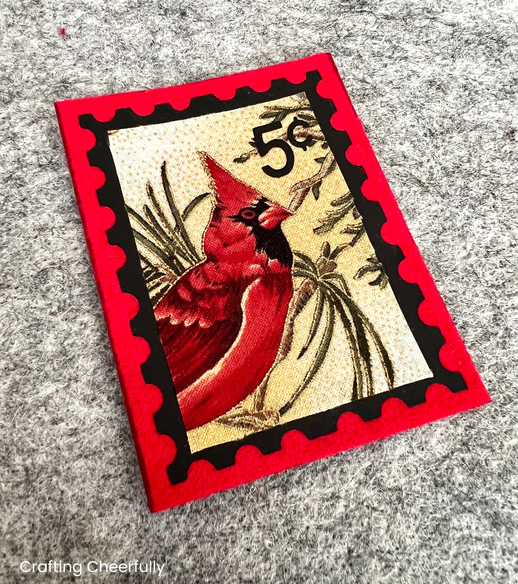The cardinal fabric is ironed to the felt rectangle inside the black stamp outline.