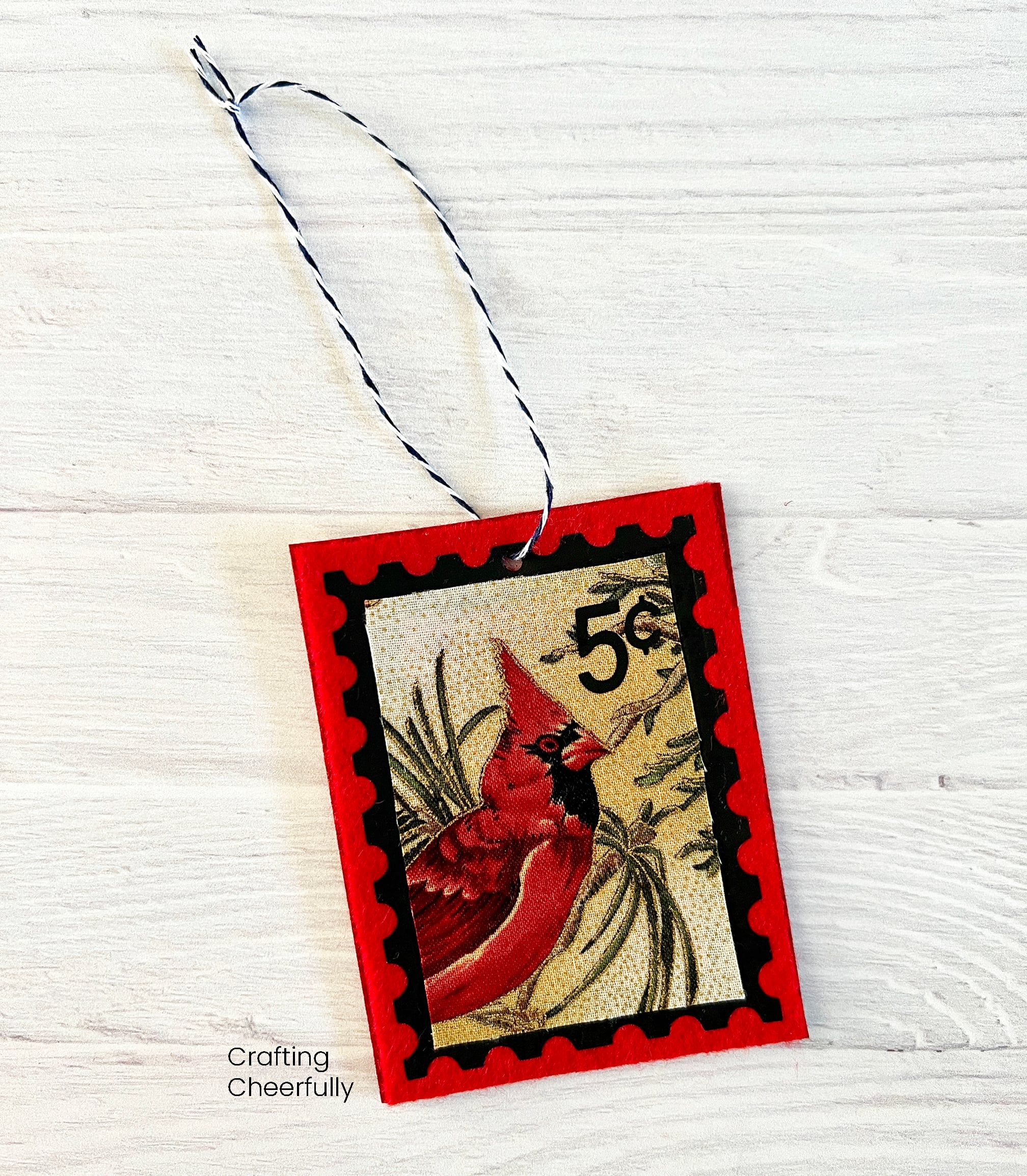 A felt postage stamp ornament with twine hanging loop.