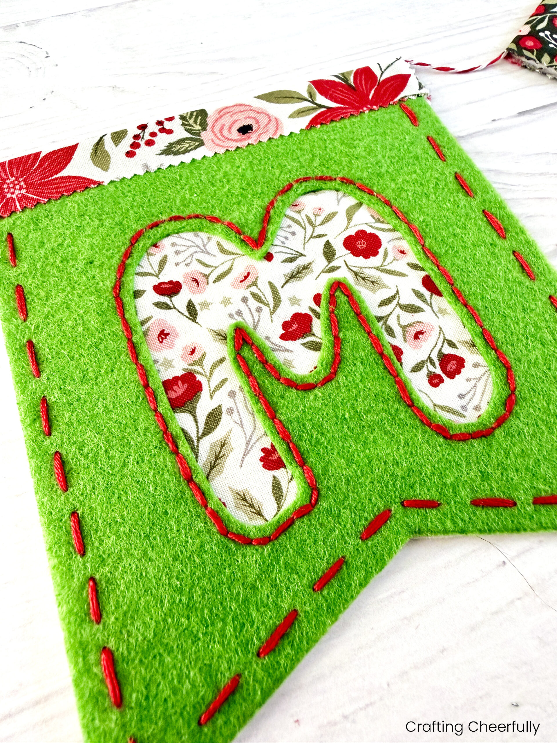 Close up picture of a felt reverse appliqué letter M pennant for a Christmas banner.