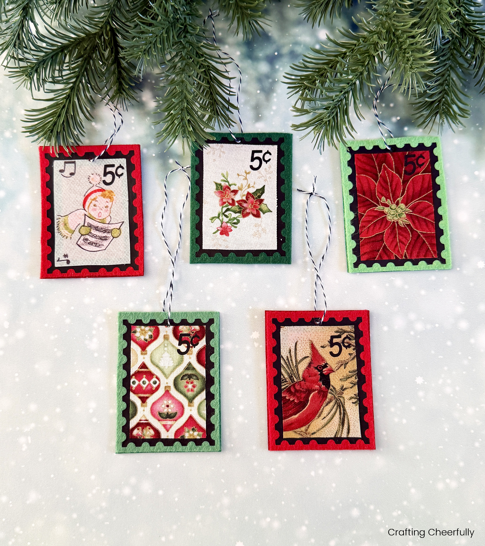 A group of five felt and fabric postage stamp ornaments hang from an evergreen tree.