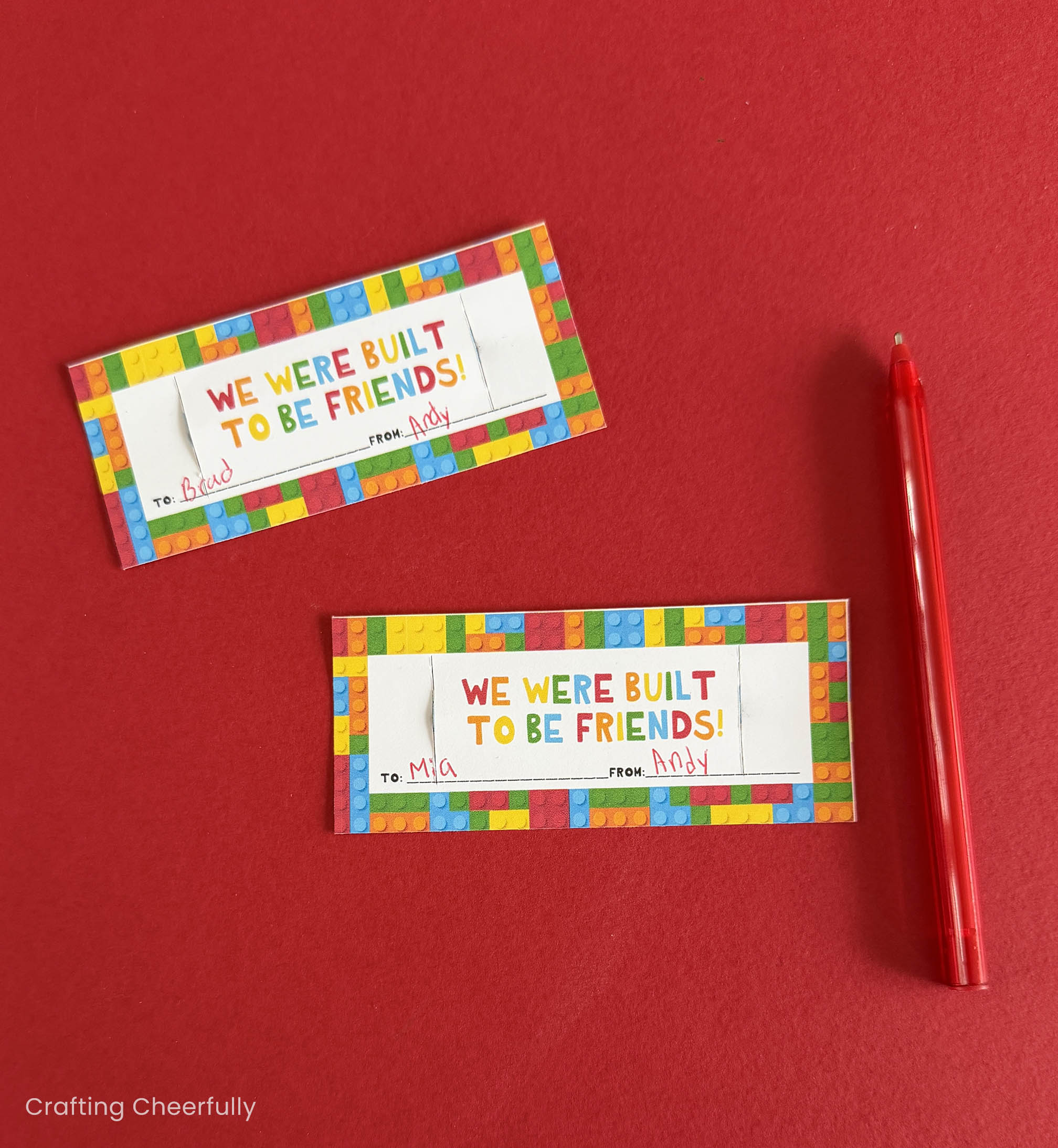 Valentines addressed to kids by kids lay next to a red pen.