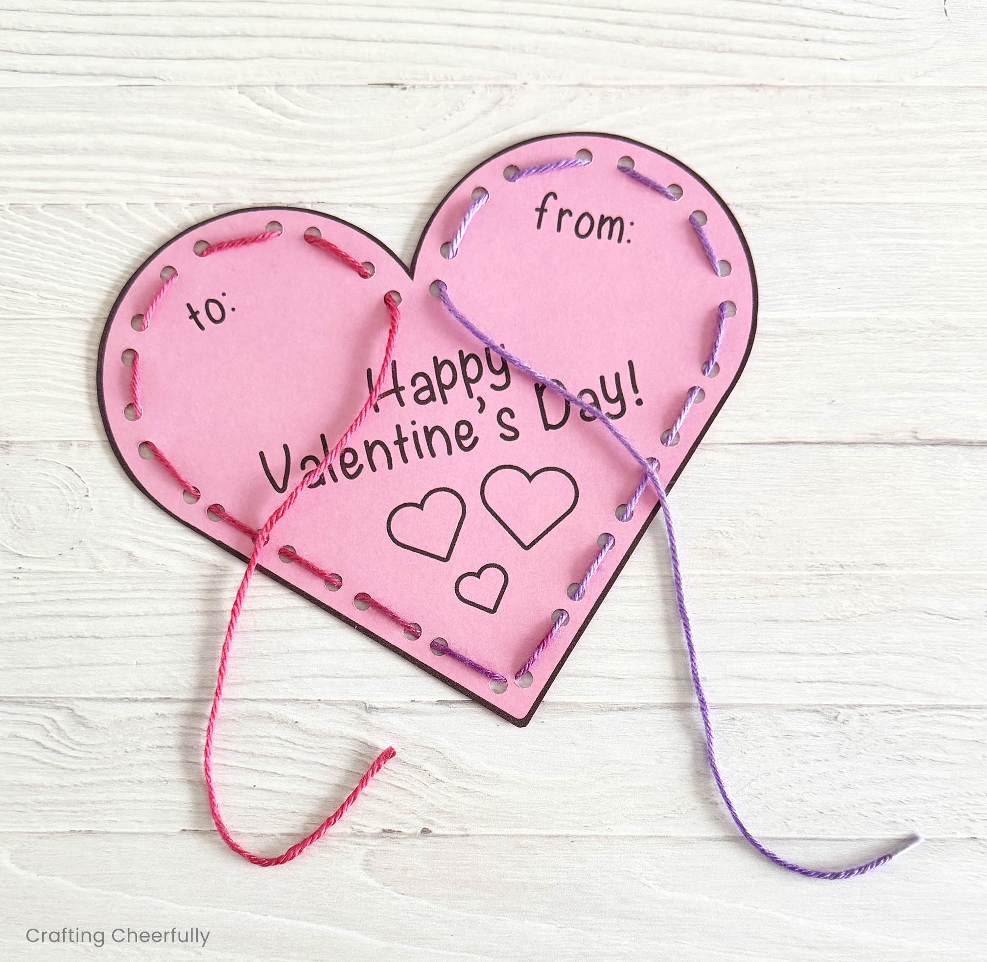 Multi-colored yarn is used to lace though the holes around the edges of the paper valentine.