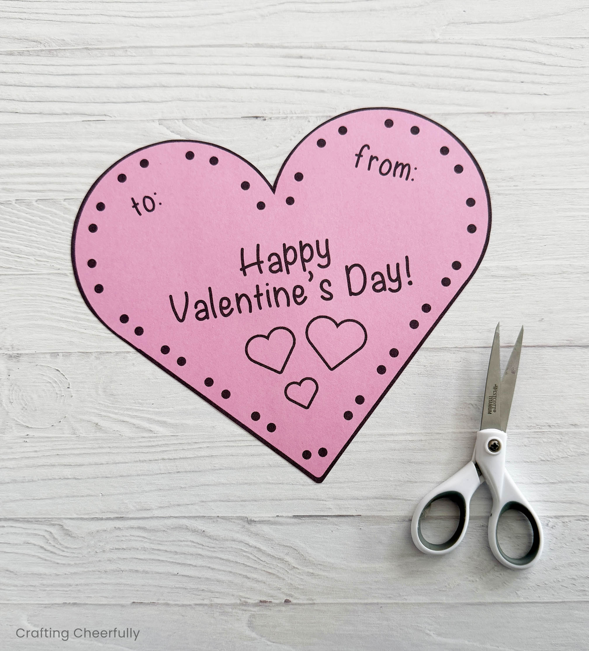 The pink heart valentine is cut out with a scissors.