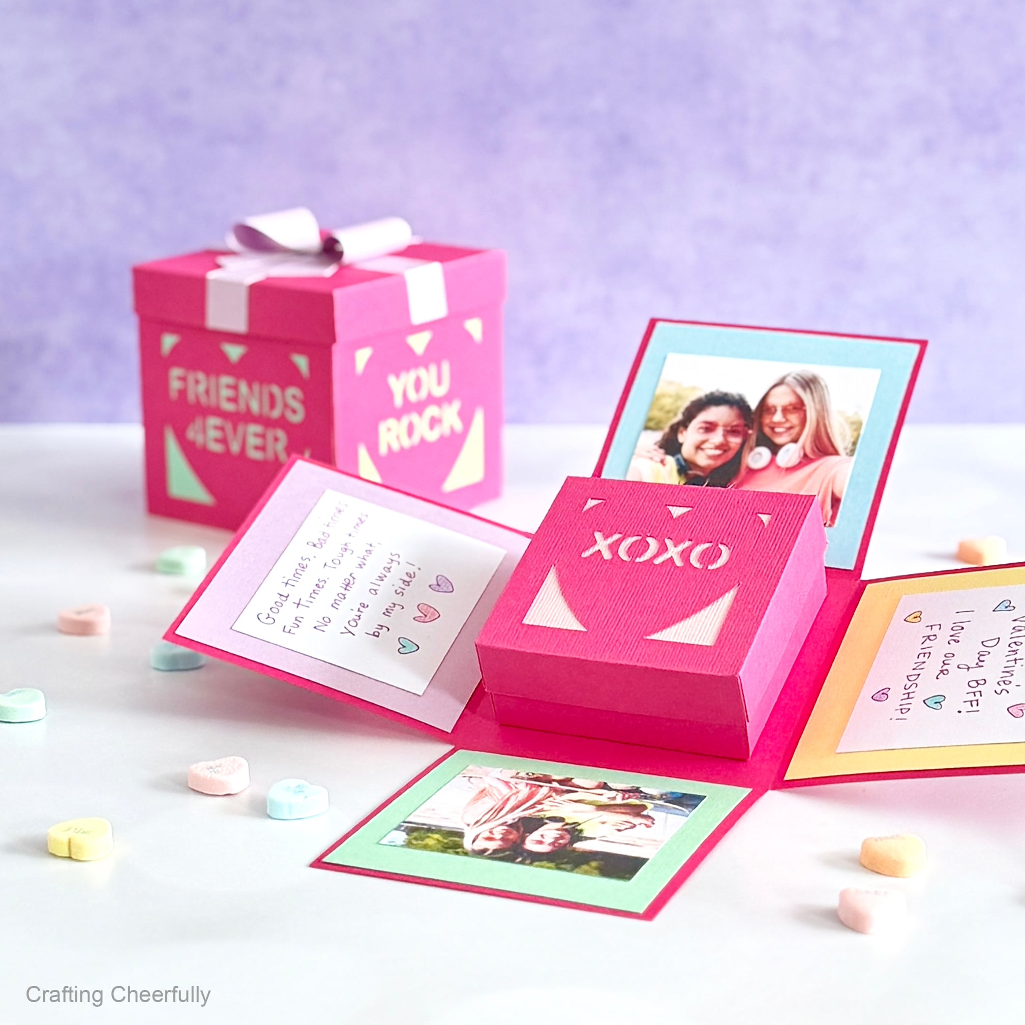 Two Valentine’s Day explosion boxes made from colorful pink cardstock. One is open revealing pictures, notes and a small heart box that reads XOXO.