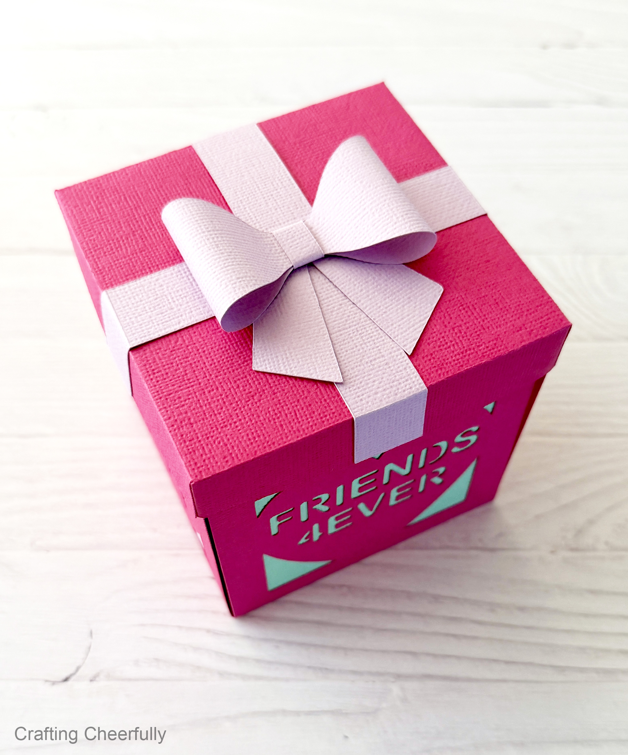 The pink conversation heart box with the lid on and a cute purple bow on top.