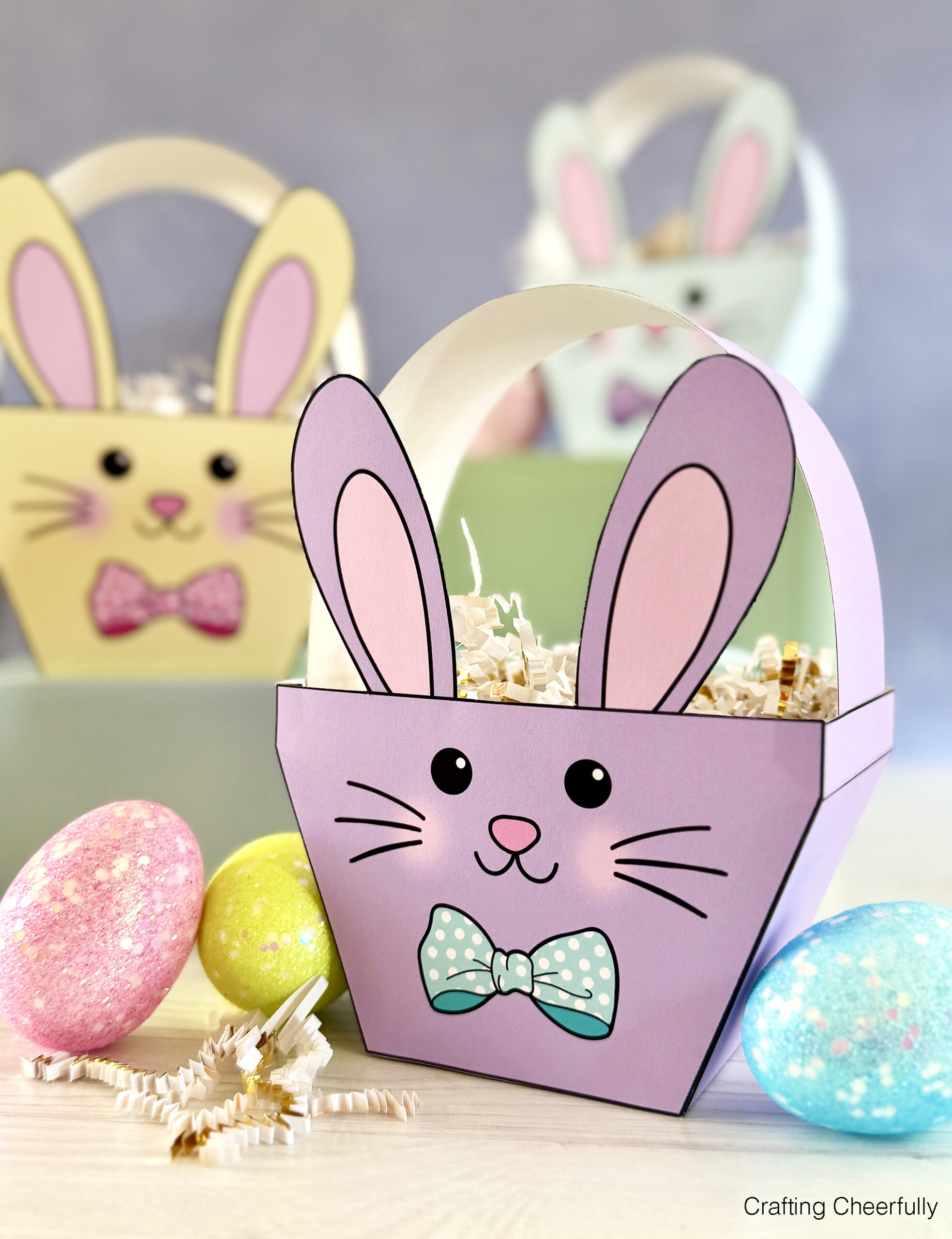 Easter bunny baskets made from paper sit next to sparkley eggs.
