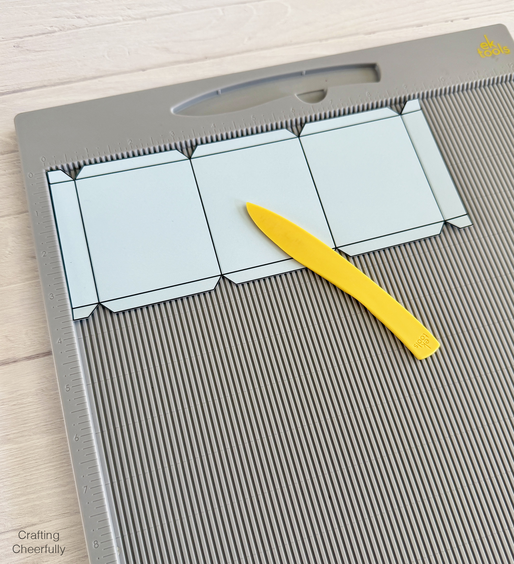 One of the box pieces is scored using a scoring board and stylus.