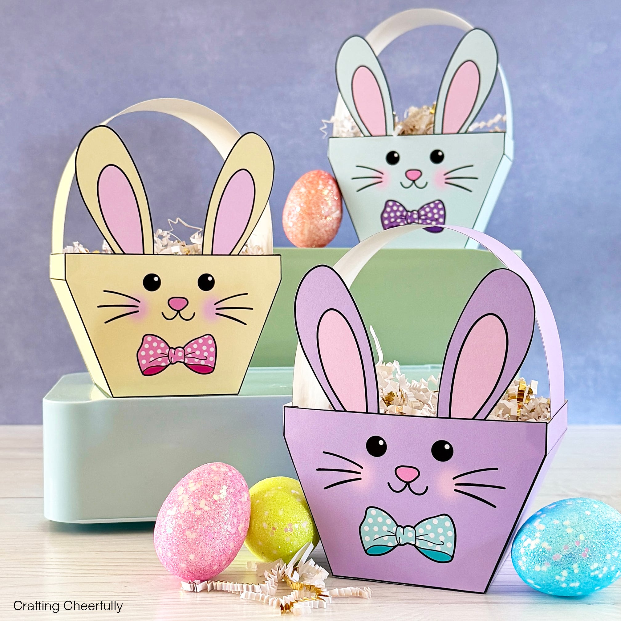 Three paper easter bunny baskets in yellow, pale green and purple.